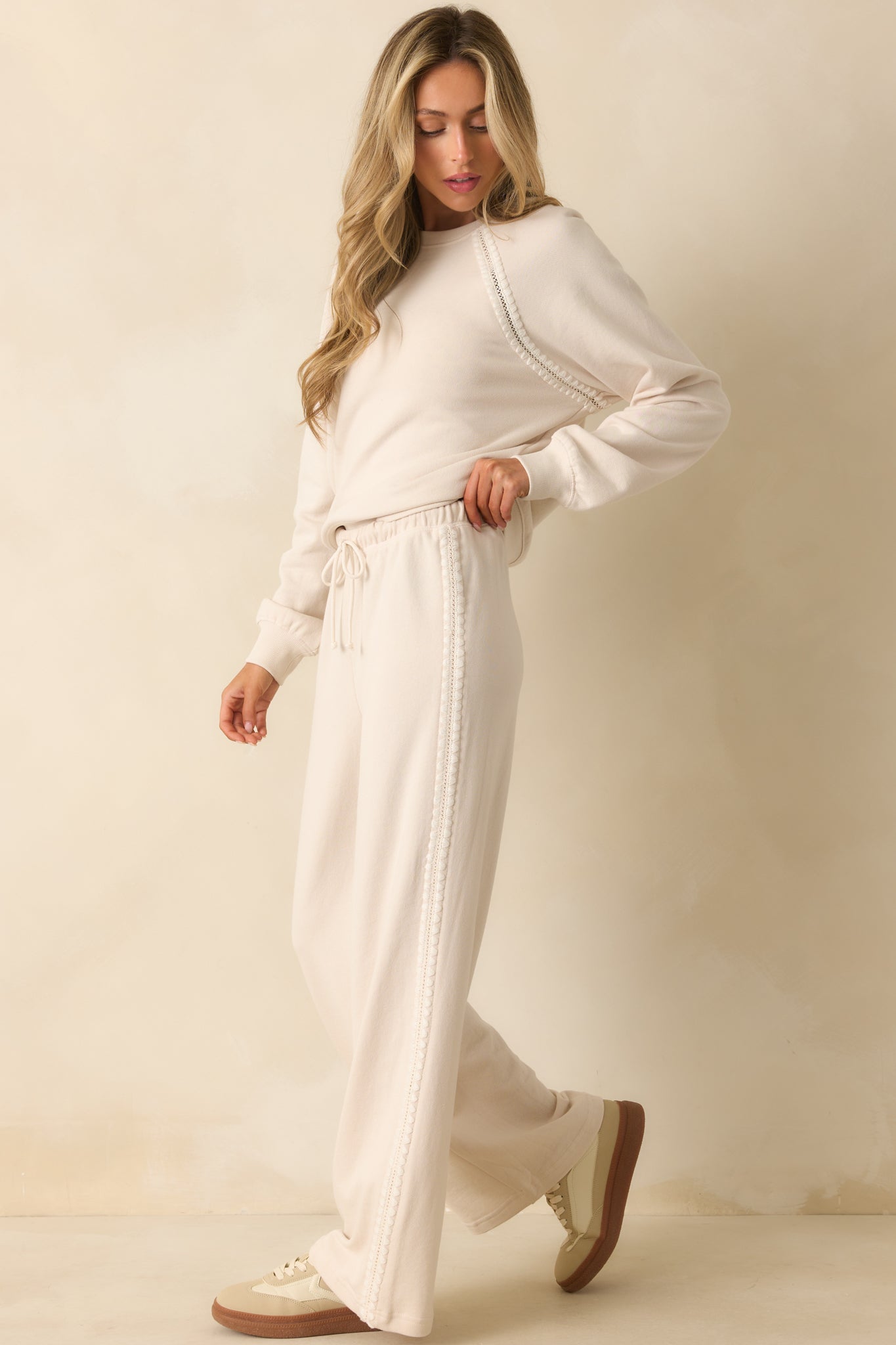 Ivory wide leg pants featuring a high-rise elastic waistband, side crochet trim, and a relaxed silhouette.