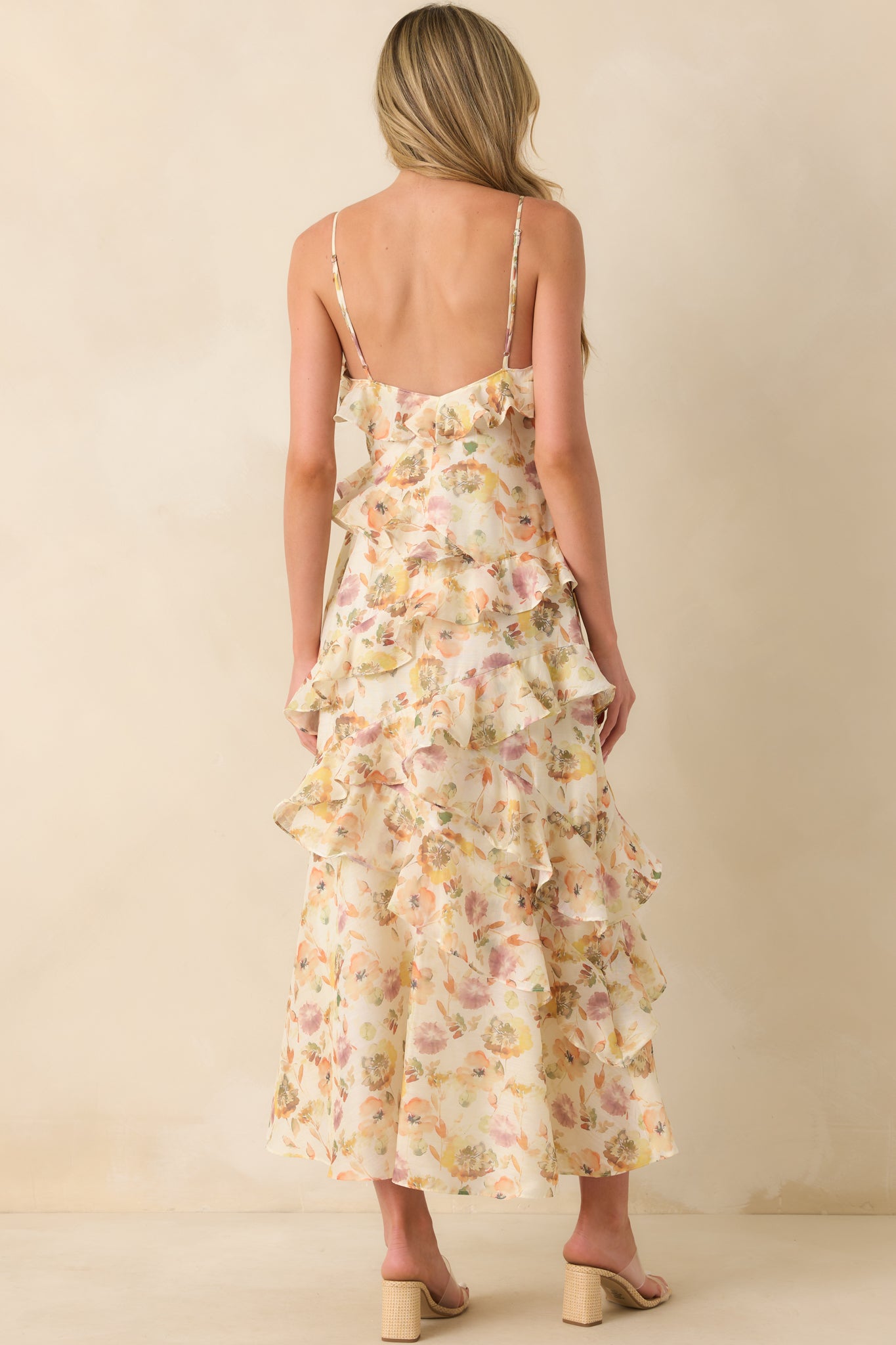 A back view of the dress highlighting the low open back, adjustable straps, and soft drape of the ruffles.