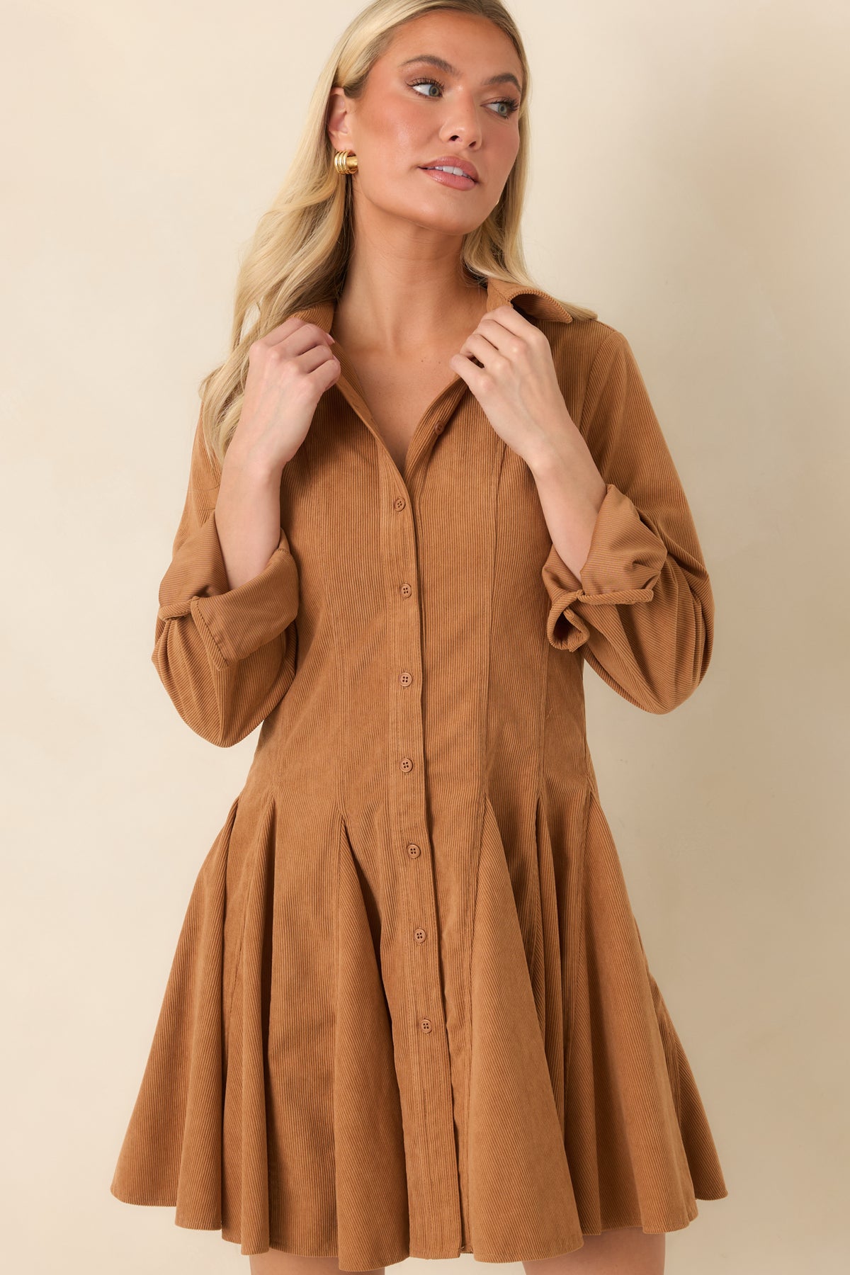 The golden camel dress features a pointed collar, full button placket, and fine vertical corduroy ridges.