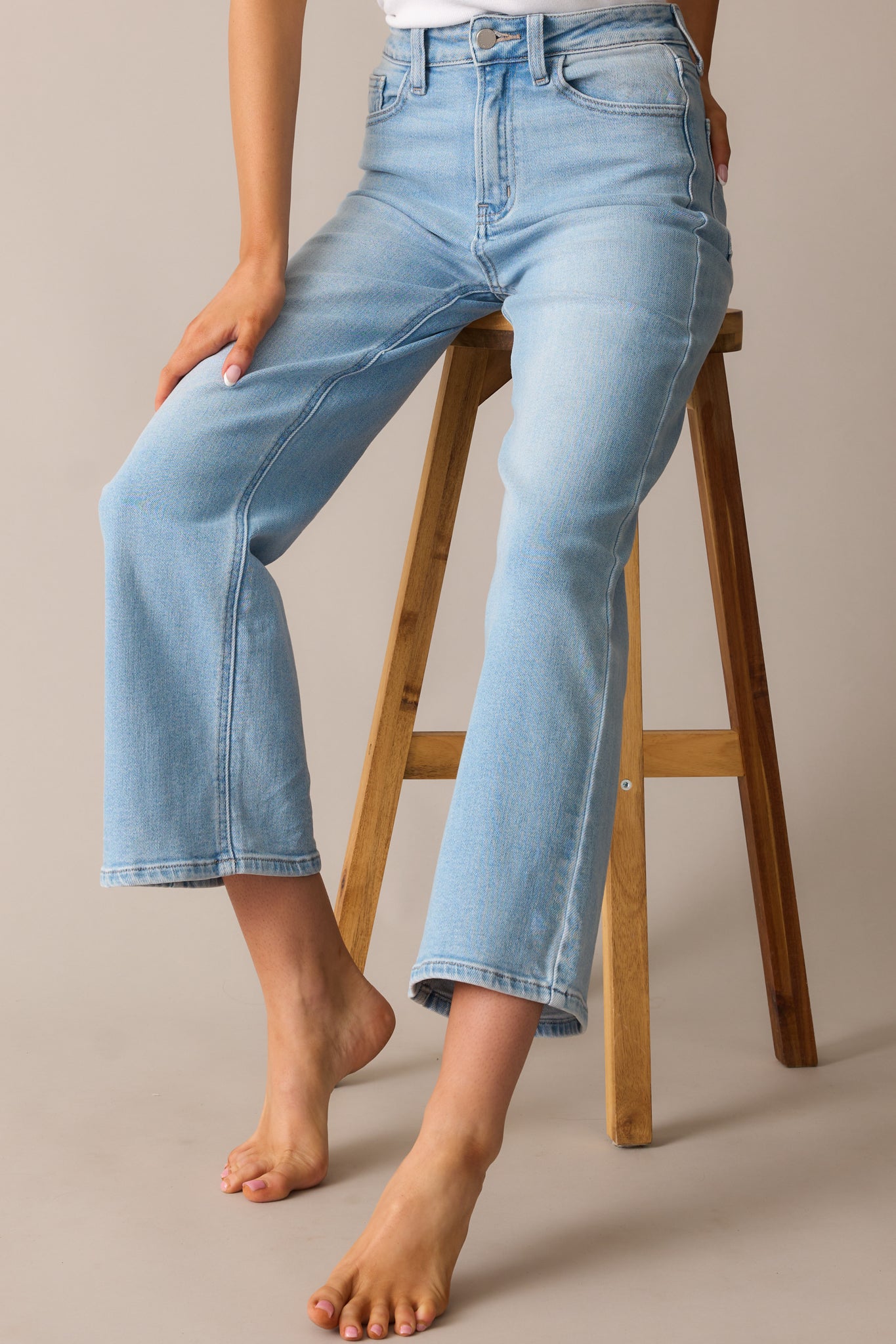 Light wash jeans featuring a high-waisted design, cropped length, and a relaxed fit.