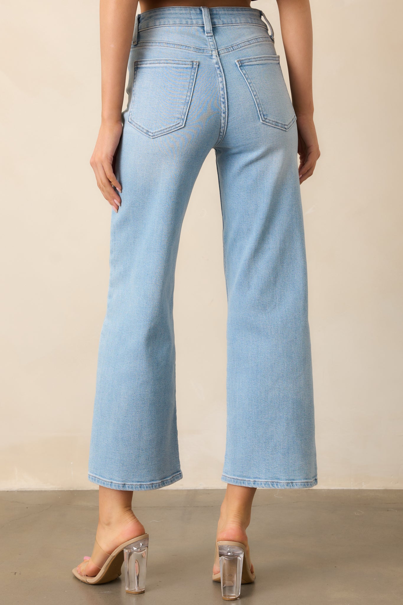 Light wash high-waisted jeans shown from behind, emphasizing the functional back pockets, belt loops, and cropped leg length.