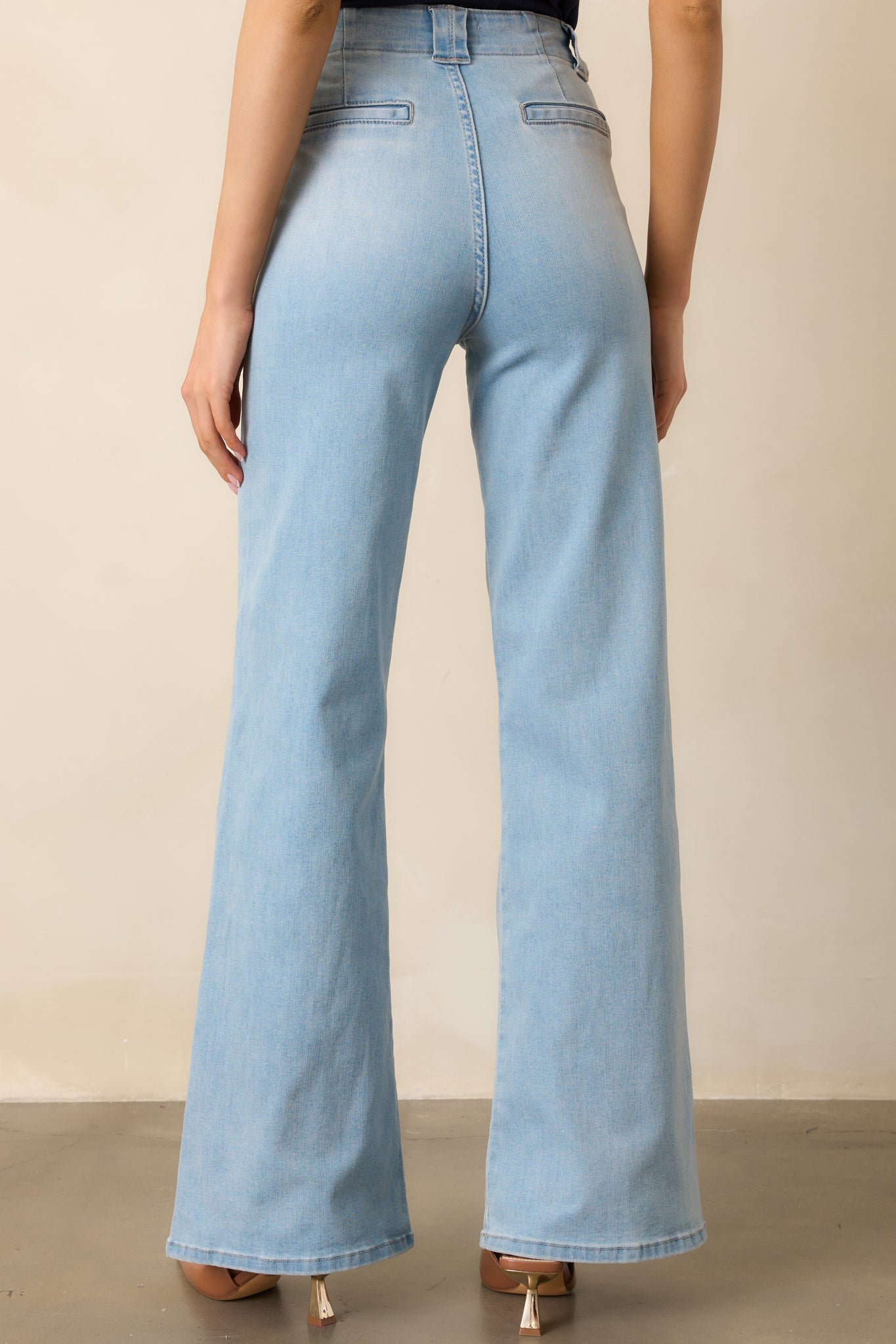 Light wash high-waisted jeans shown from behind, emphasizing the fit, belt loops, and flared leg silhouette.