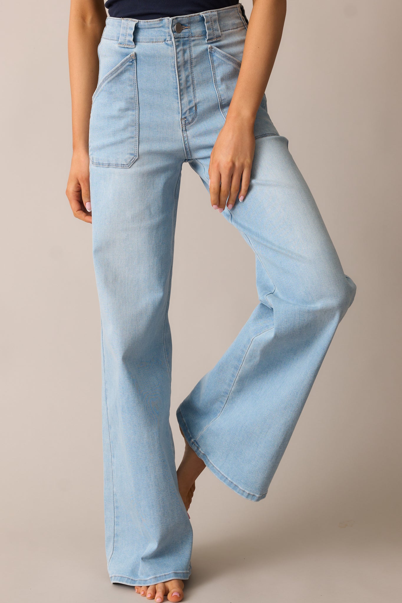 A close-up of the light wash jeans, emphasizing the high-waisted fit, belt loops, and smooth denim fabric.