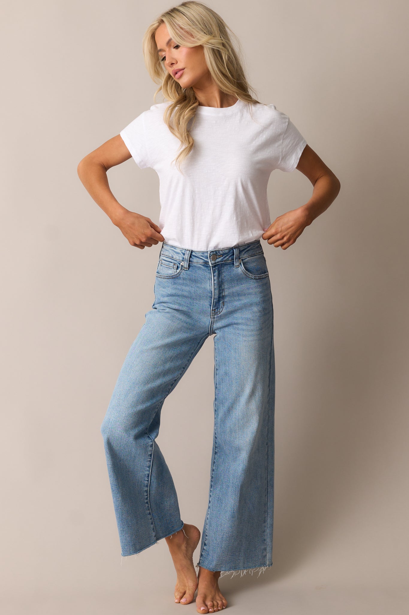 Light wash jeans featuring a high-waisted fit, wide-leg silhouette, and raw hem.