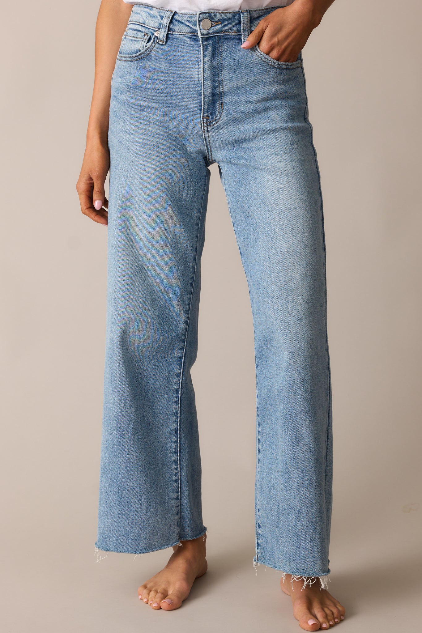 Light wash wide-leg jeans with a slightly cropped length, raw bottom hem, functional pockets, and a classic button and zipper closure.