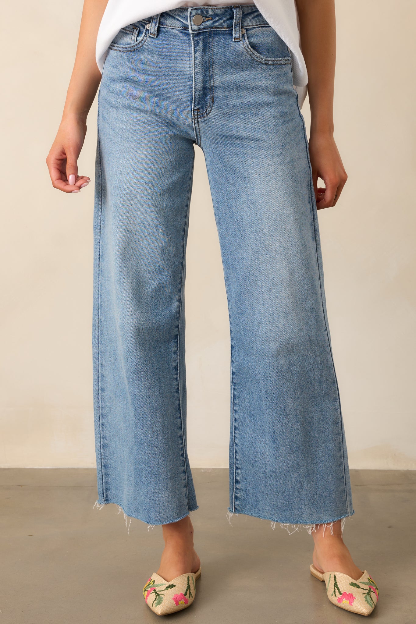 Close-up of the waistband on the light wash jeans, highlighting the belt loops, functional pockets, and secure zipper and button closure