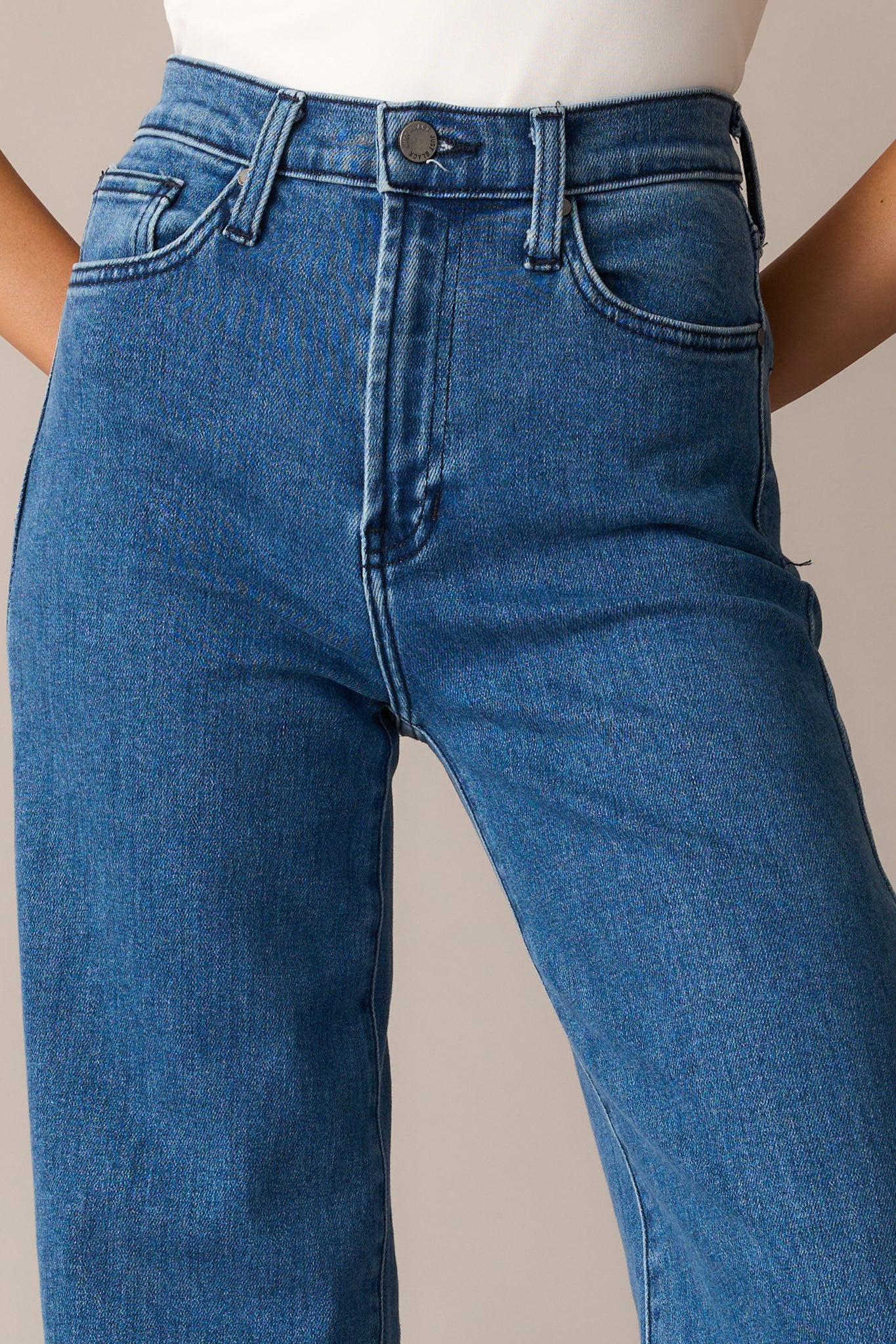 A close-up of the jeans’ button and zipper closure, emphasizing the stitching, waistband, and durable denim material