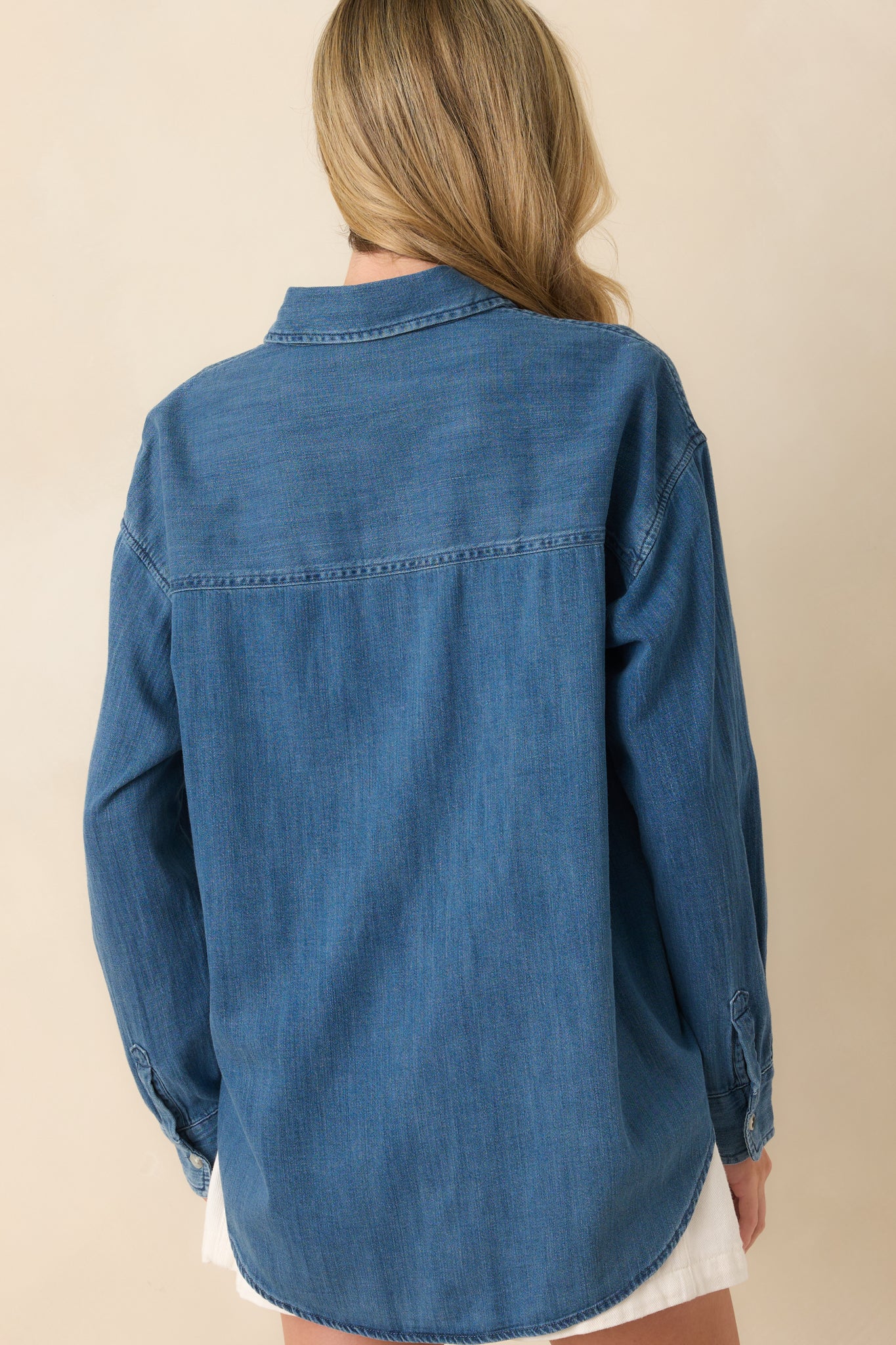 Rear view of the top showing the straight back panel, long sleeves, and relaxed drape of the medium wash fabric.
