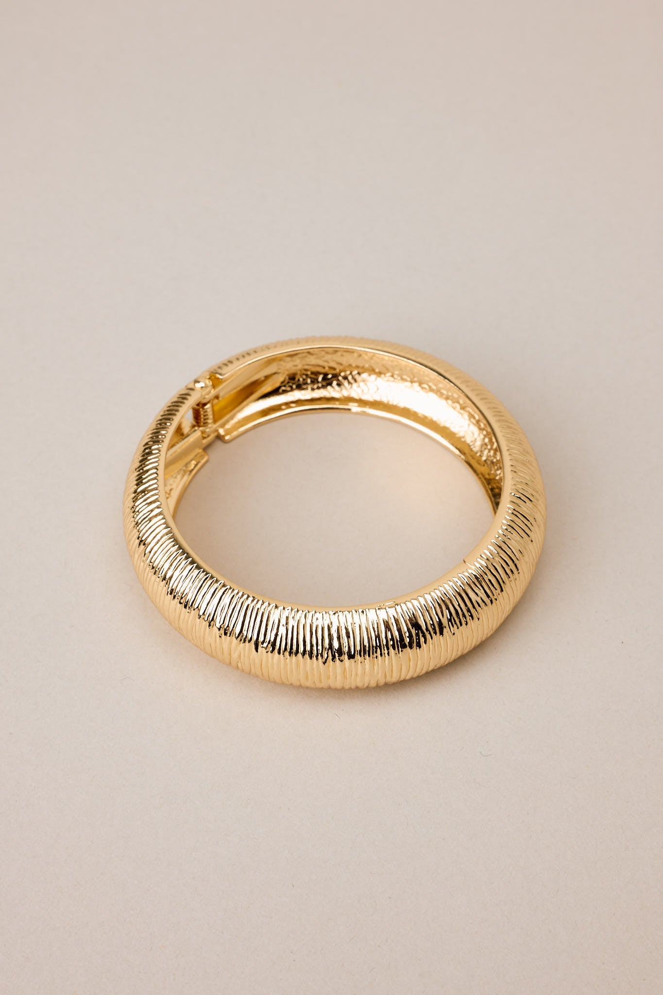 An overhead view emphasizing the symmetrical oval shape and sturdy gold hardware of the bracelet.