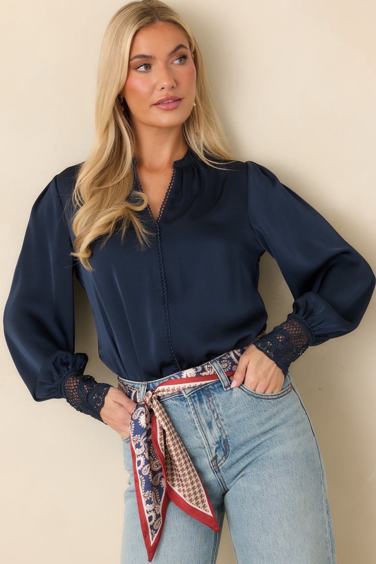 Model wearing a navy blue blouse with a lace-trimmed split neckline, long balloon sleeves, and wide lace cuffs.