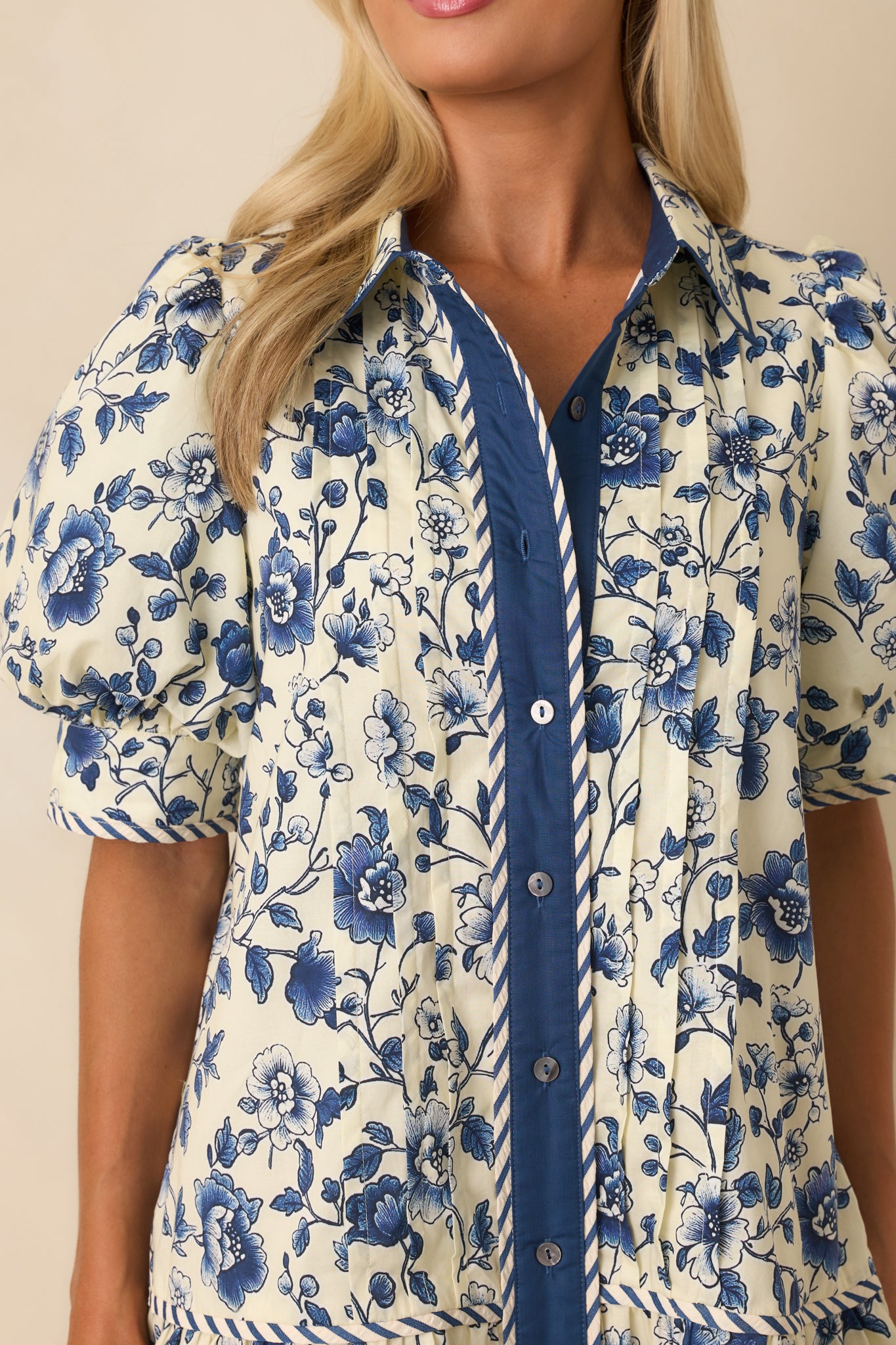 Close-up of the button front, vertical pintucks, and stripe trim detailing on the navy floral mini dress