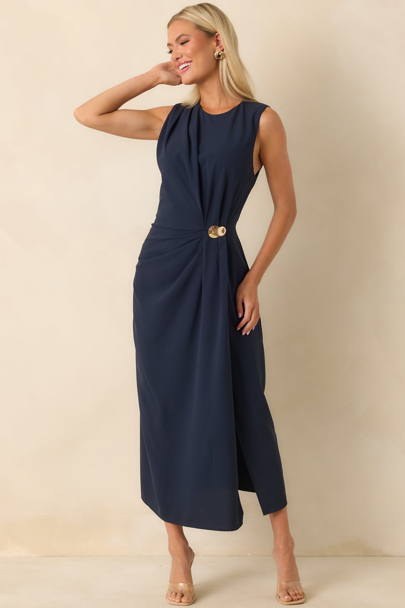 Front angle of the navy dress showing the sleeveless cut, soft ruched texture, and decorative gold detail.