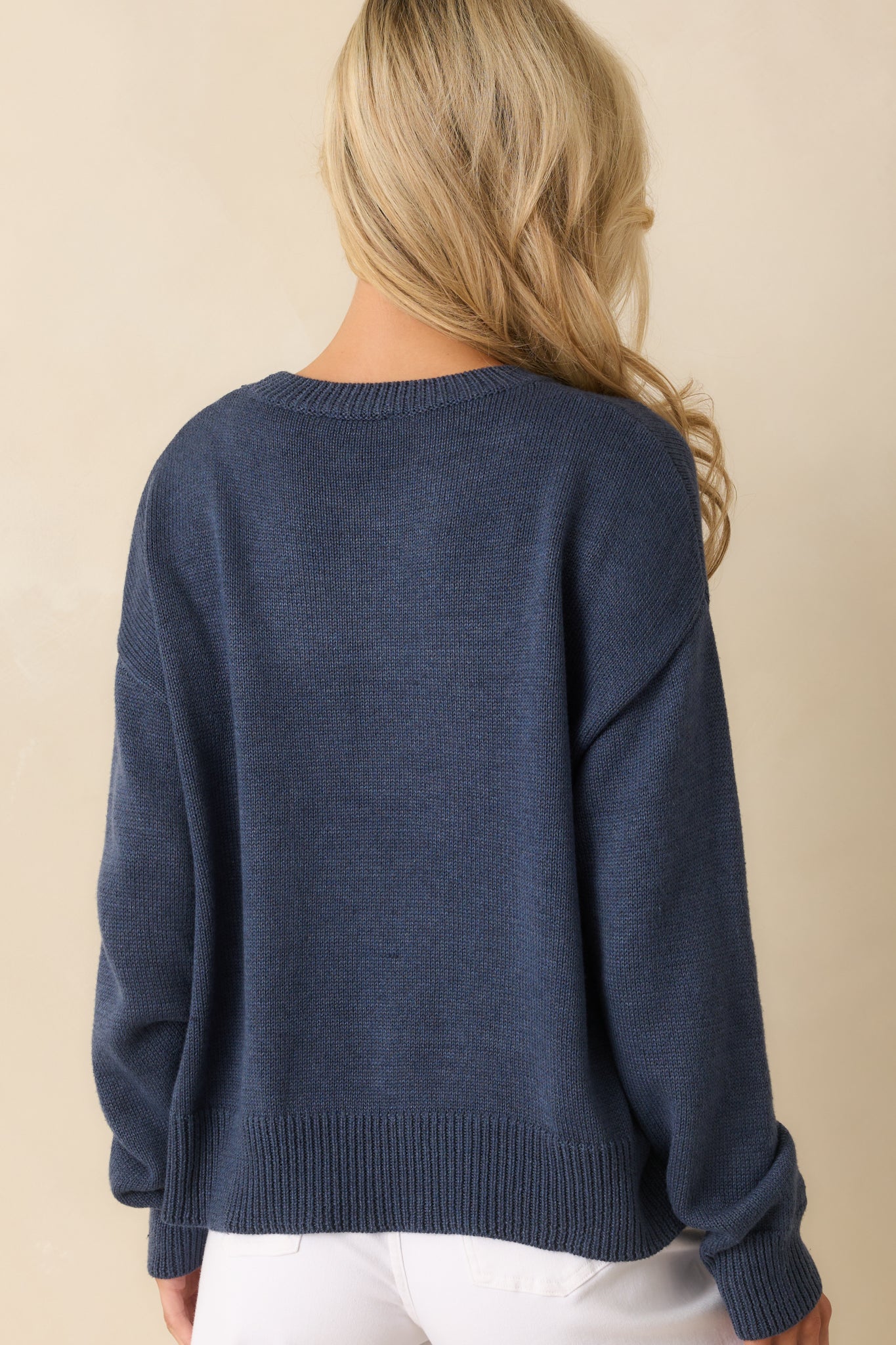 Rear view of the navy knit pullover sweater with long sleeves and ribbed trim.