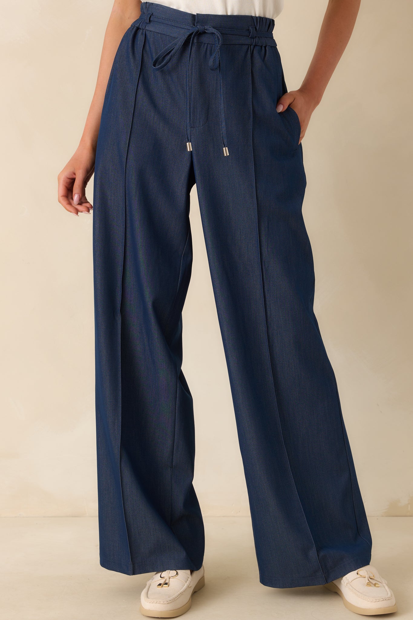 Cropped front view focused on the waistband, showing the hook and bar button closure and small belt loops.