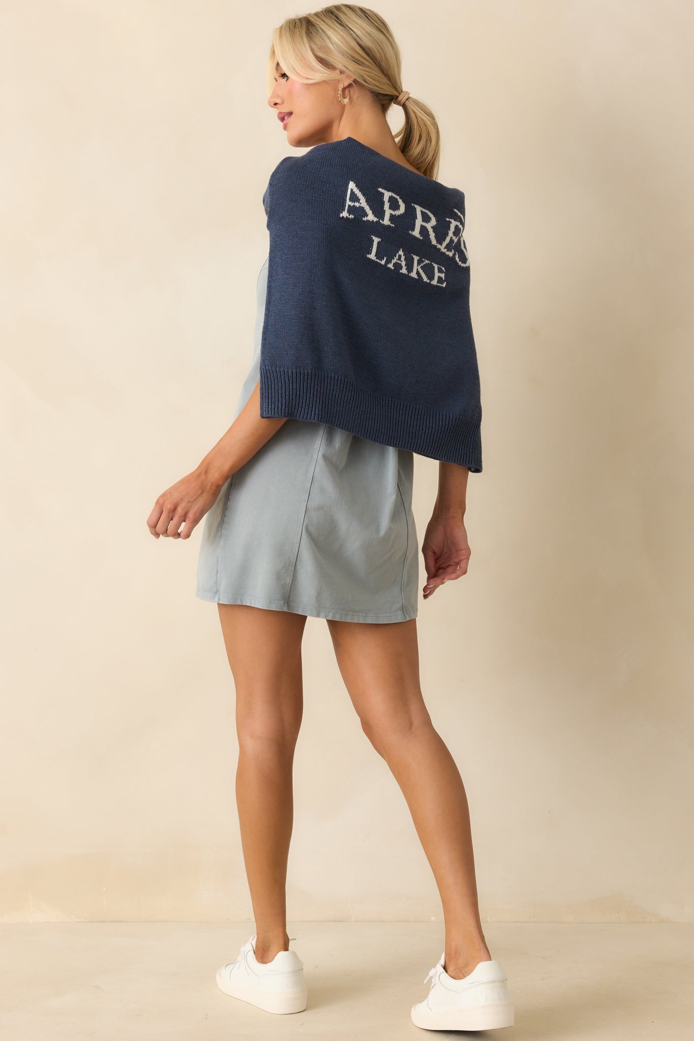 Navy pullover sweater with bold white text detail across the chest and ribbed hemline.