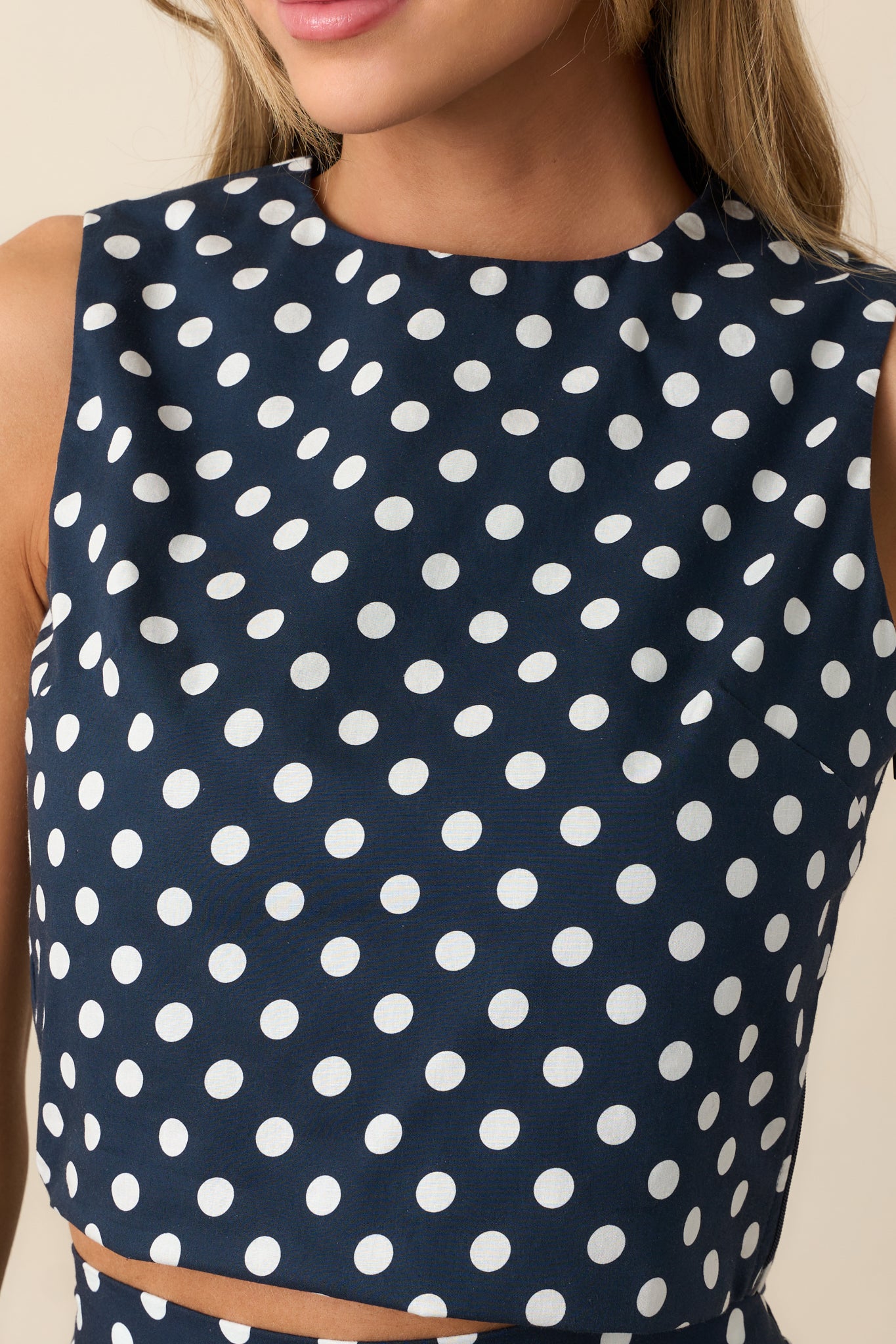Detailed view of round neckline and polka dot fabric on navy crop top.