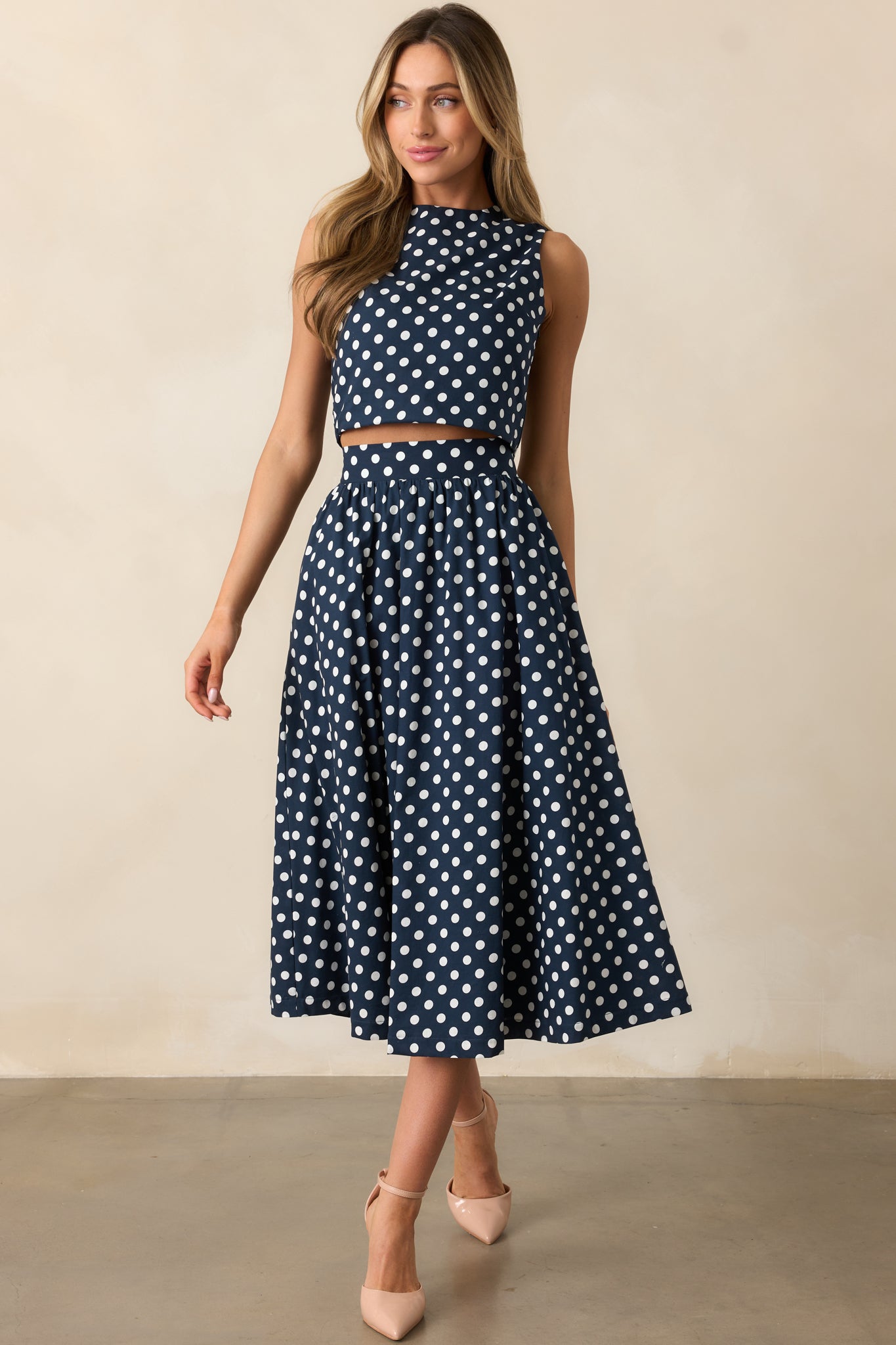 Navy and white polka dot sleeveless crop top displayed from the front.