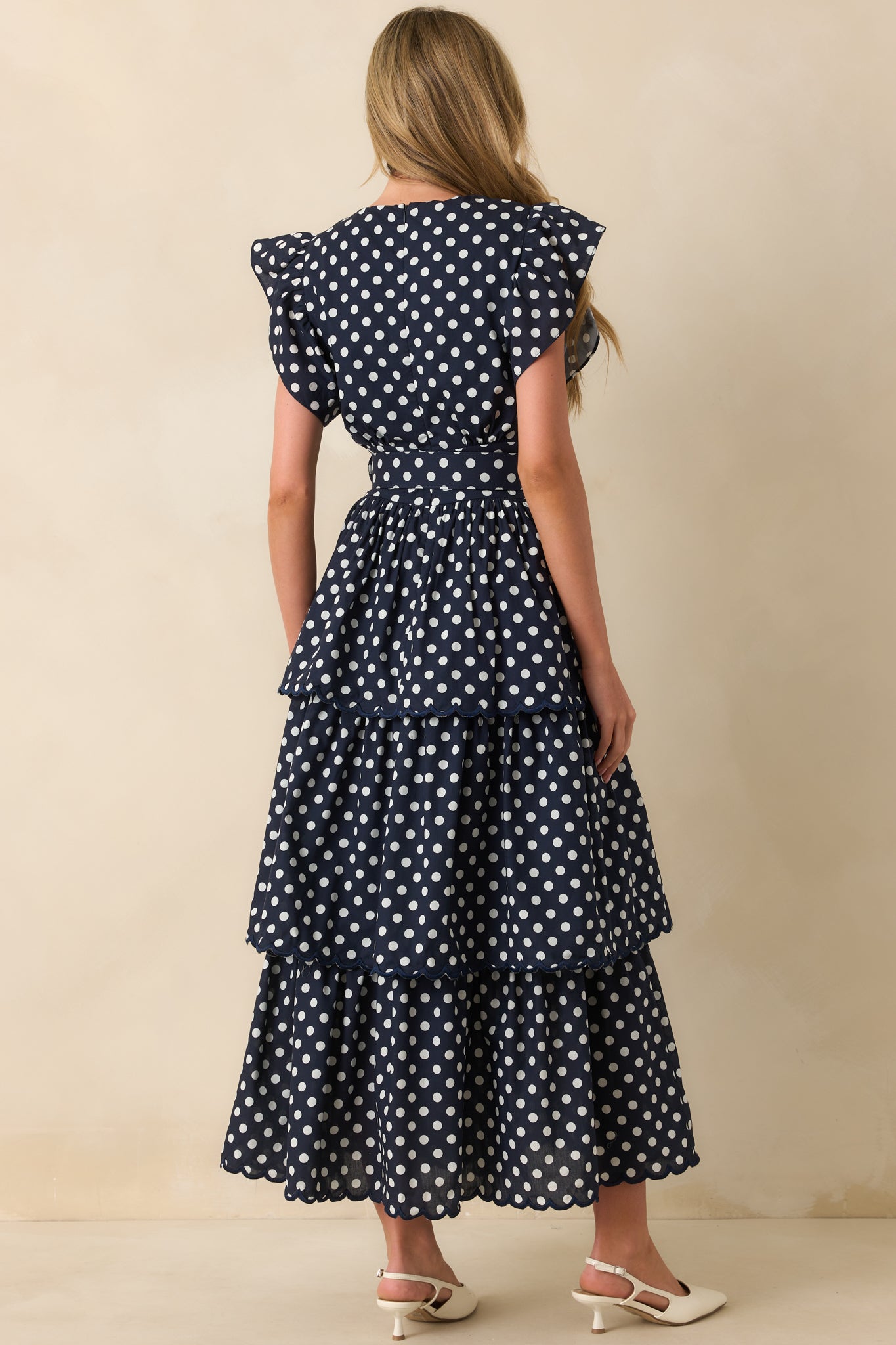 A view from behind of polka dot maxi dress with hidden zipper and flutter sleeves.