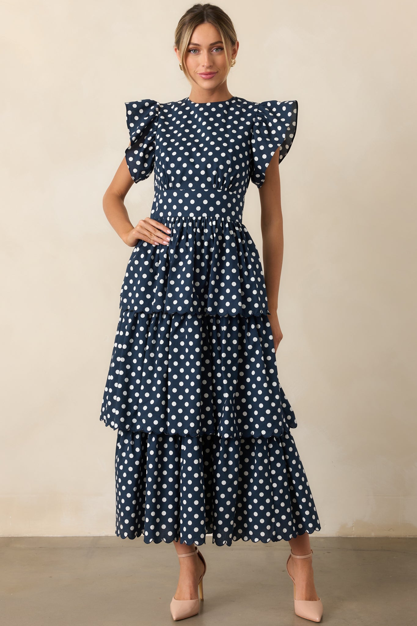 Navy and white polka dot dress with flutter sleeves and optional belt displayed from the front.