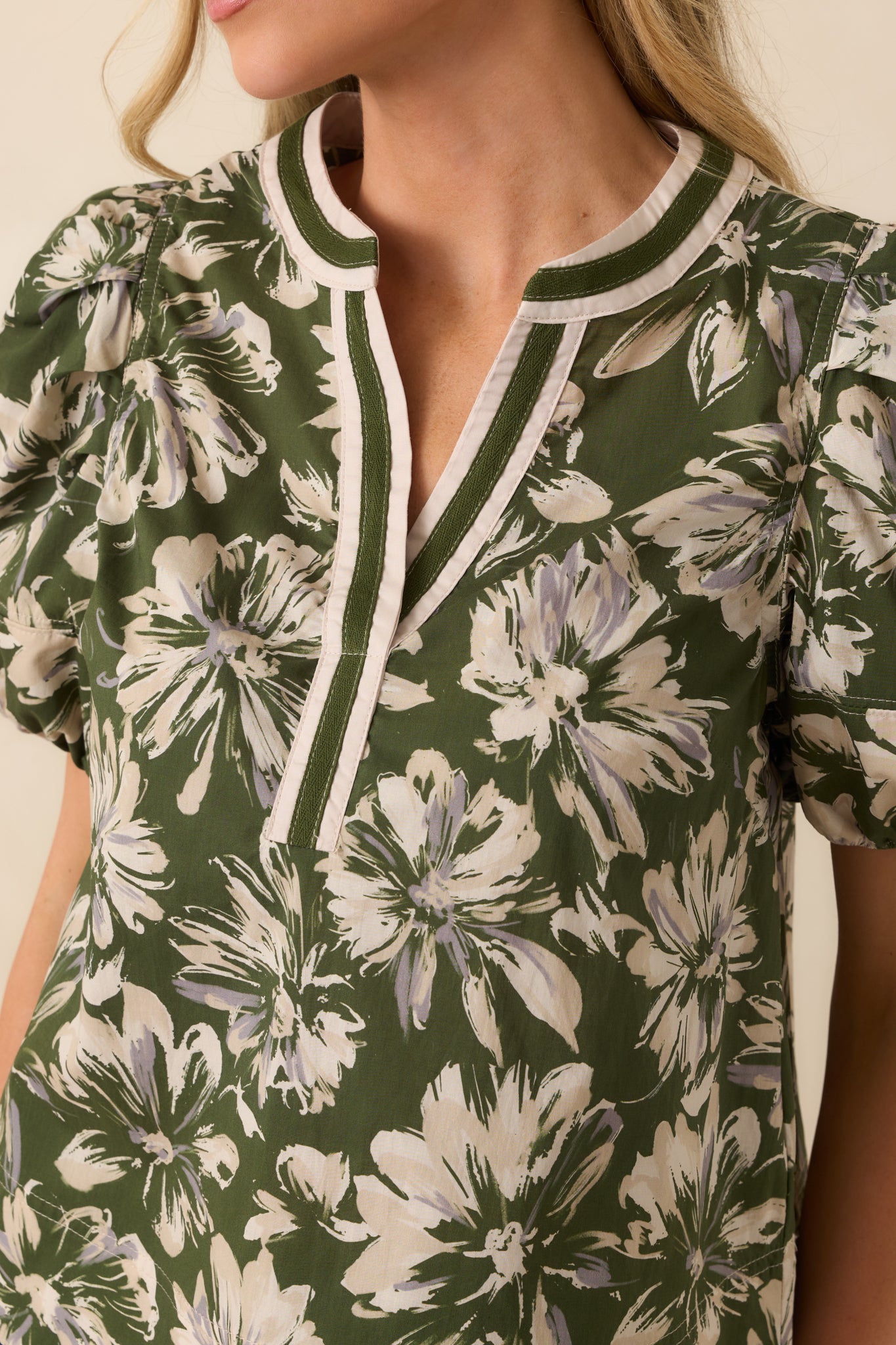 Close-up of the olive green top fabric showing ivory floral print, contrast trim, and fine topstitching.