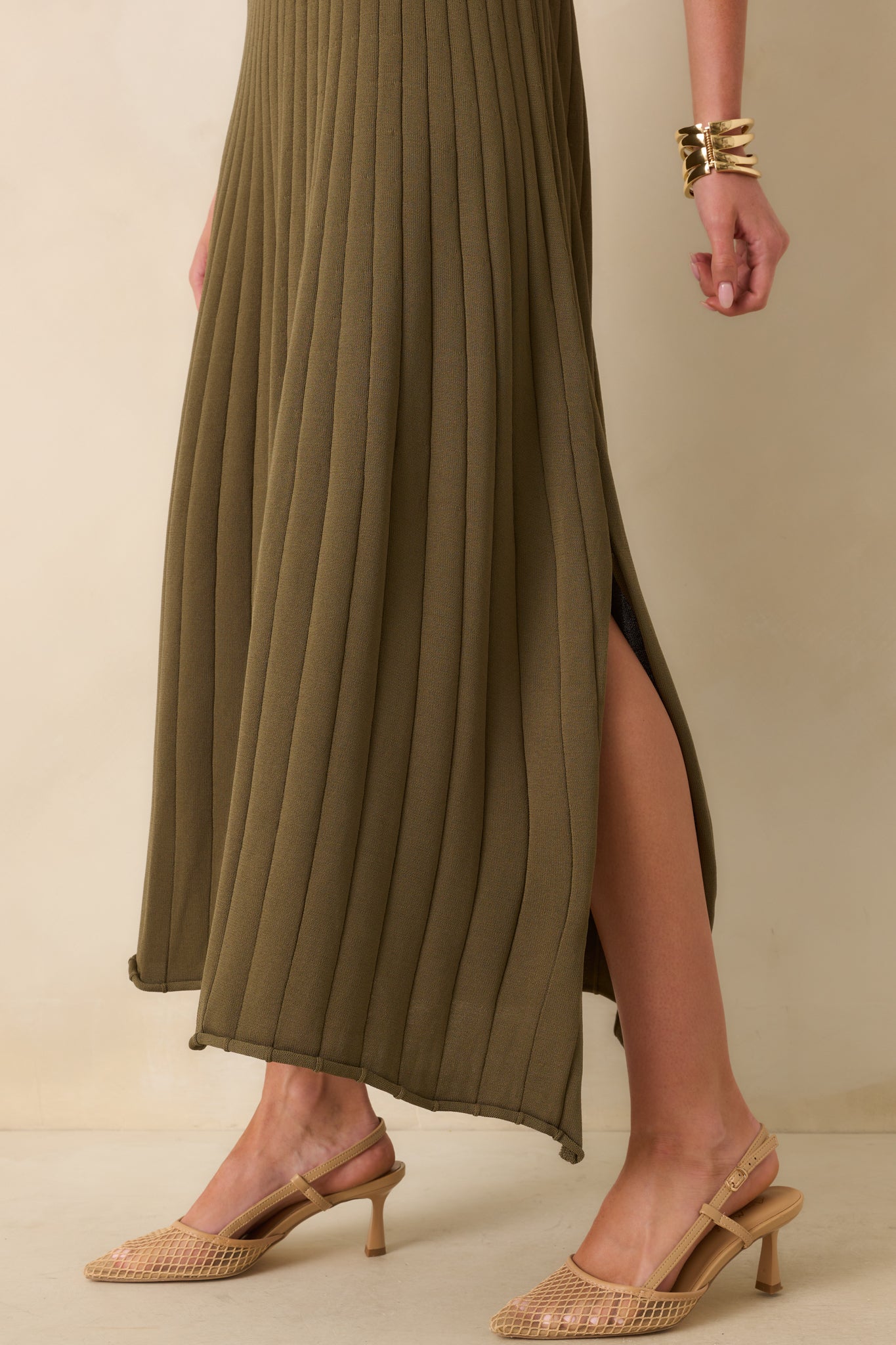Rolled bottom hem and side vent slit detail of olive green midi dress with flowy skirt.