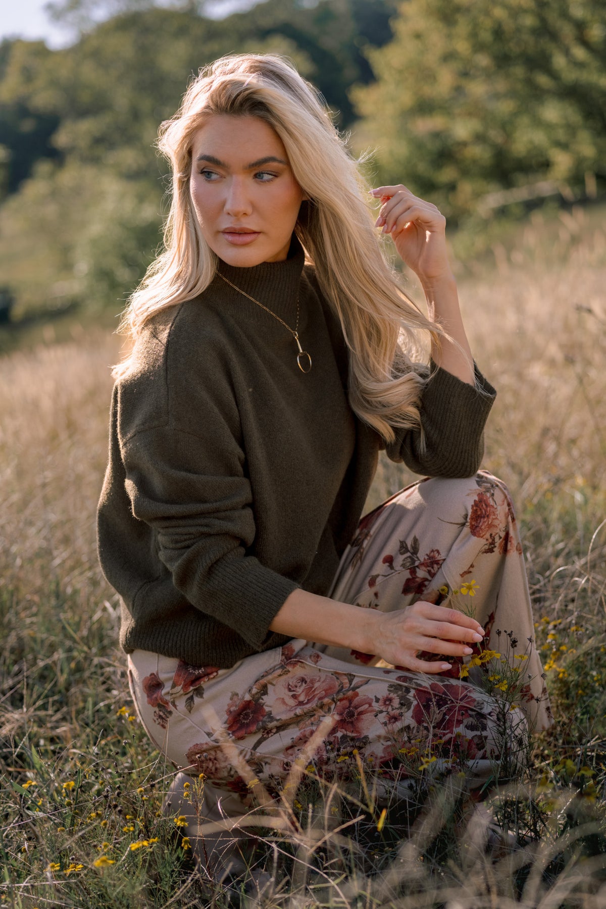 Model wearing an olive green mock-neck sweater with relaxed long sleeves and ribbed cuffs and hem.