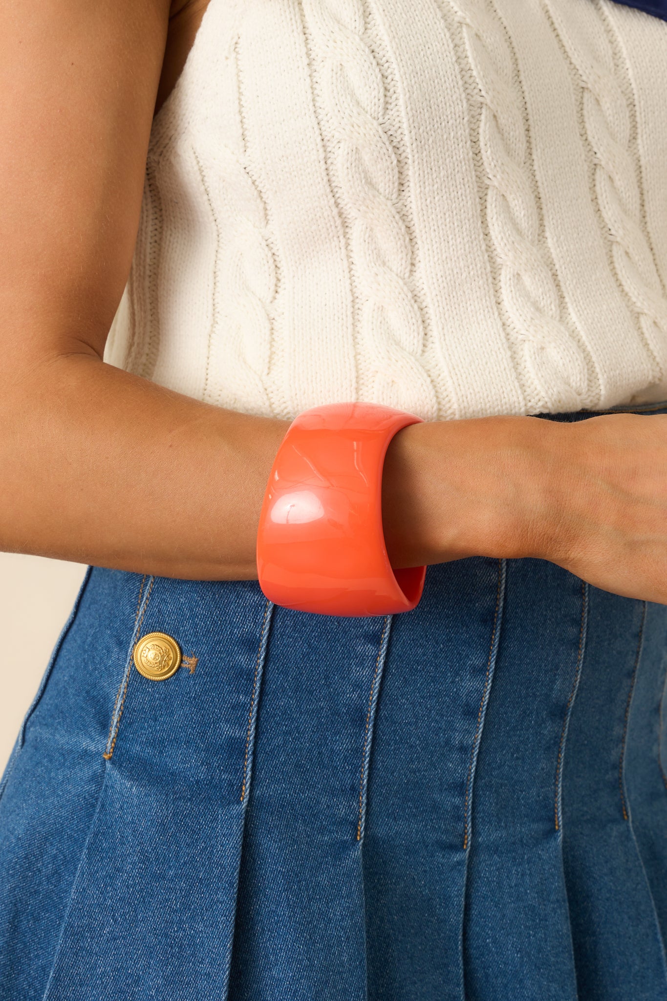 View of the smooth high-polish texture on the orange statement bangle.