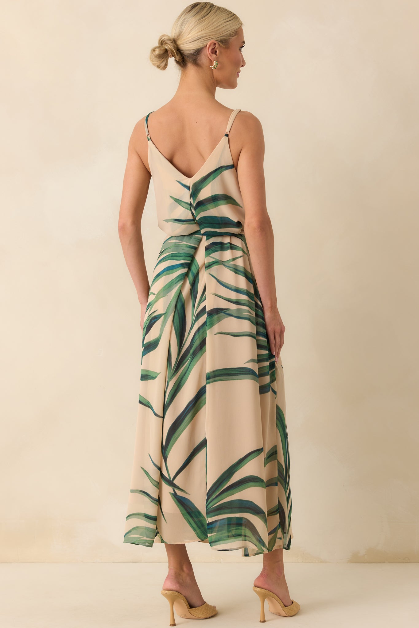 Full body back view of model in a beige maxi dress with a green palm leaf chiffon overlay and deep V-back, styled for a tropical vacation look.