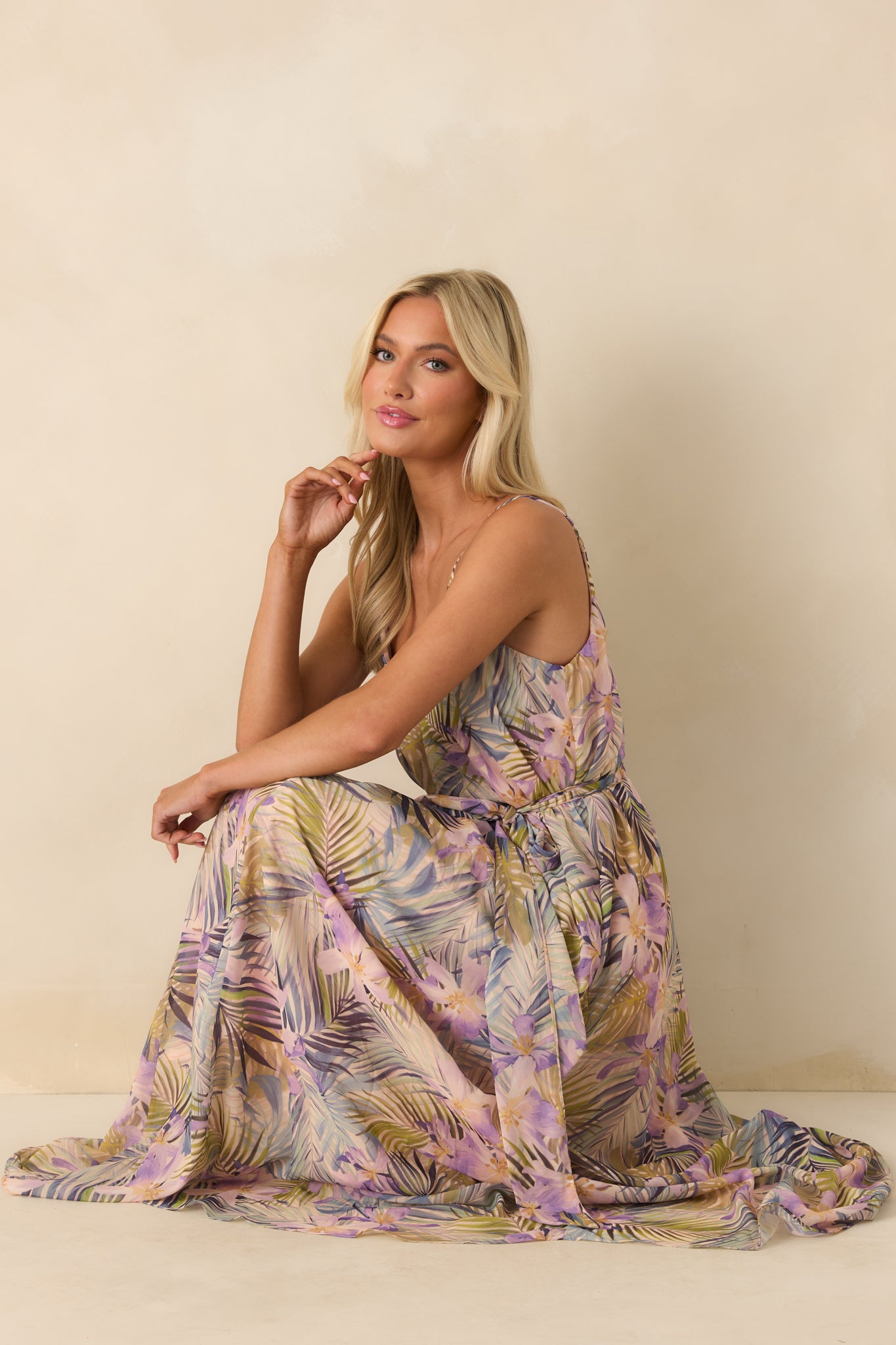 A side view of the light pink maxi dress featuring a multicolor tropical print chiffon overlay and deep v-neckline.