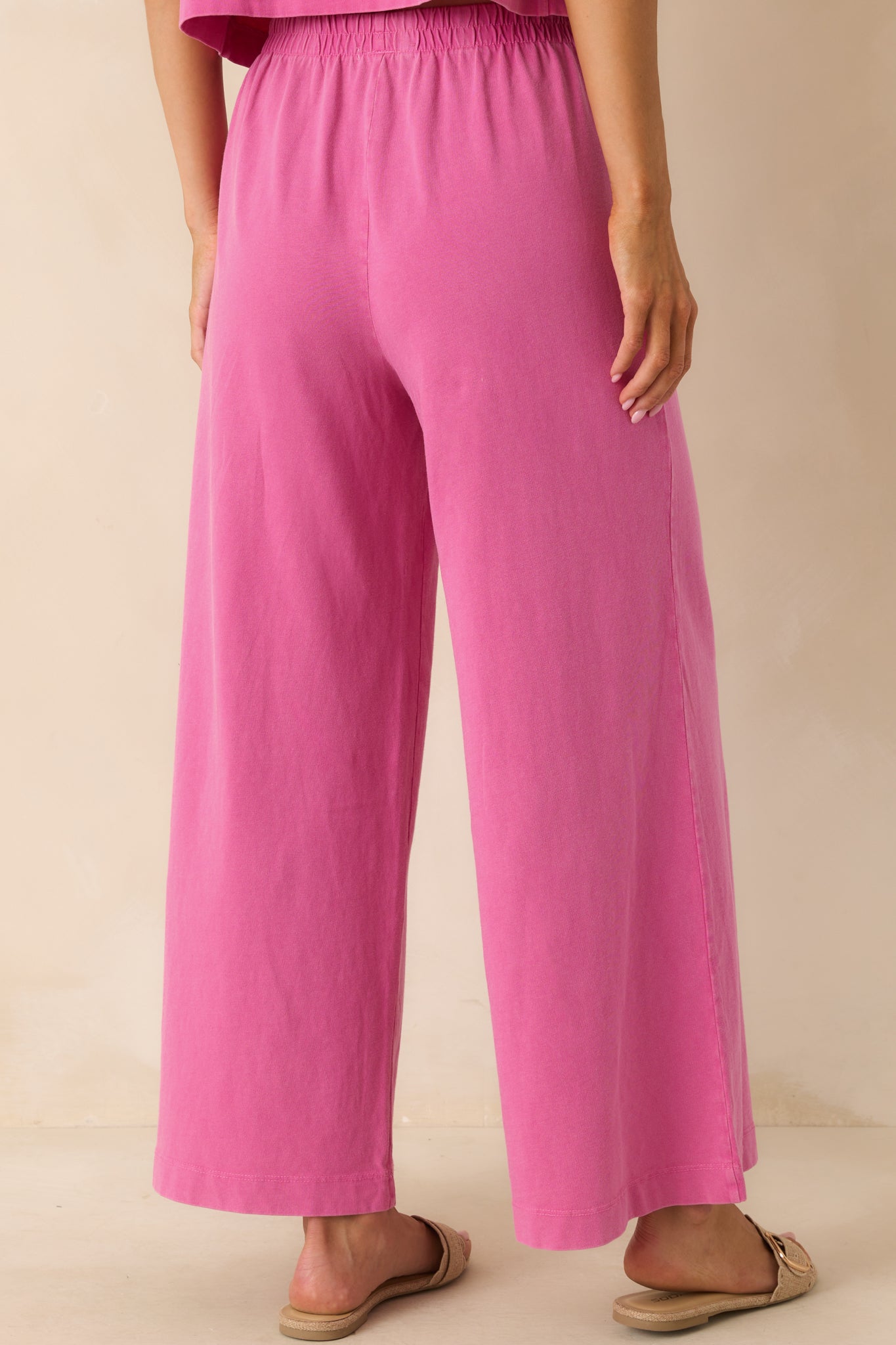 A view from behind of the island pink pants showing the relaxed fit, high waist, and flowing wide legs from the back.