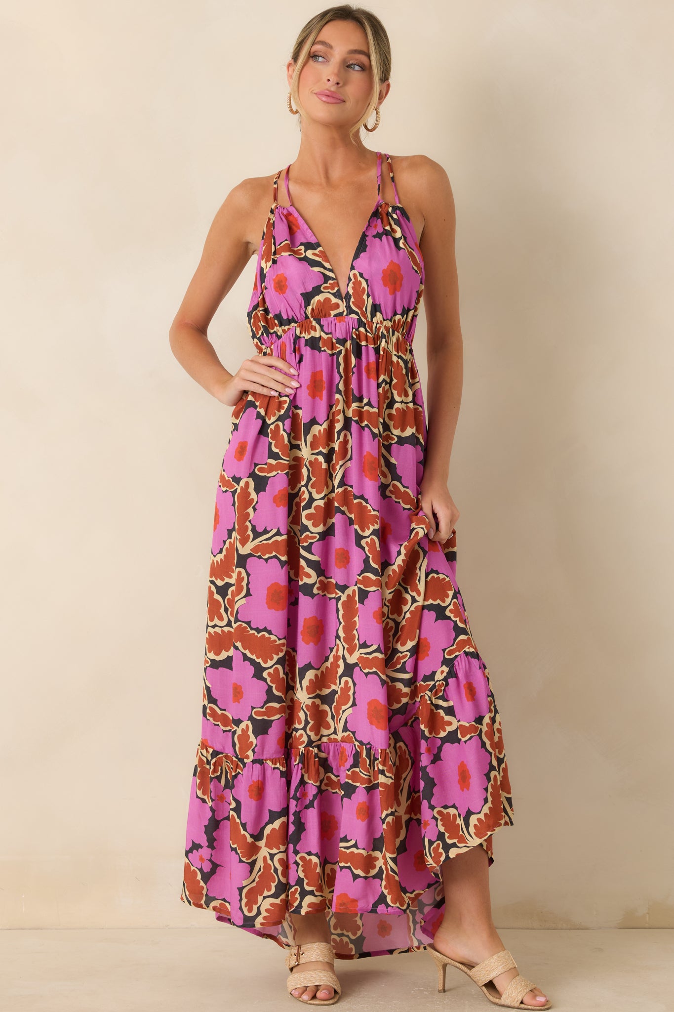 Pink floral empire waist maxi dress with adjustable spaghetti straps and a flowing tiered skirt shown from an angled front view.