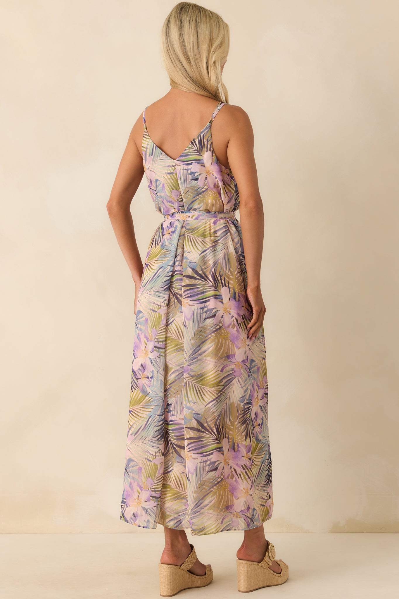 A back view of the maxi dress featuring a v-back design, adjustable spaghetti straps, and the continuous tropical print pattern.