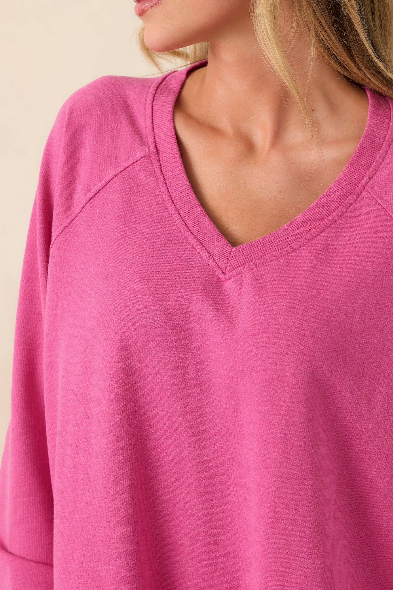 Close-up of the v-neckline on the island pink sweatshirt, showing the soft cotton fabric and ribbed edging along the collar.