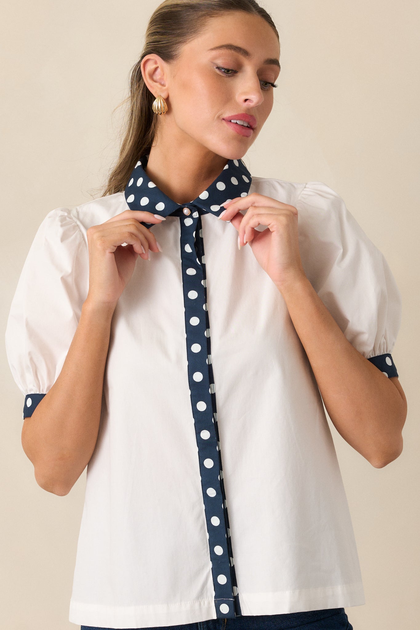 Close-up of the navy polka dot collar and functional buttons on the white cotton top.
