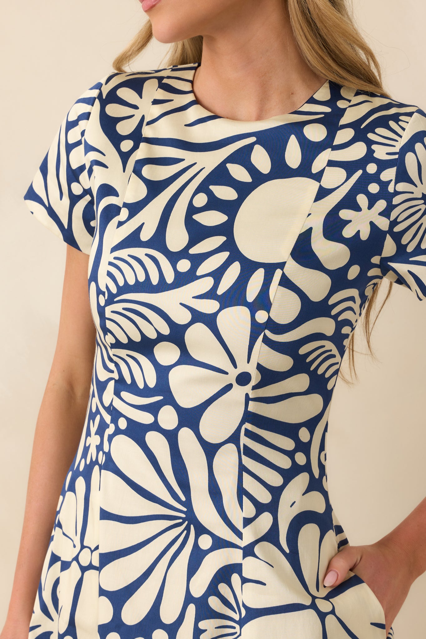 Close-up of reversible midi dress showing floral print, fabric texture, fitted waist, and pocket detail.