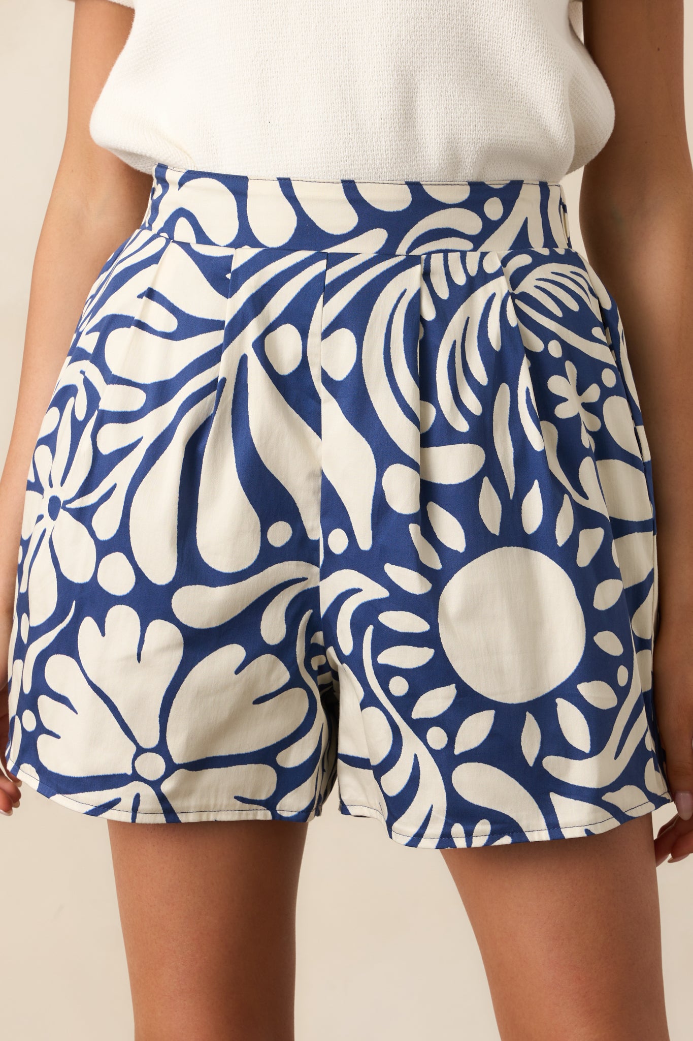 A close-up detail of the floral print pattern and pleated leg design on the shorts.