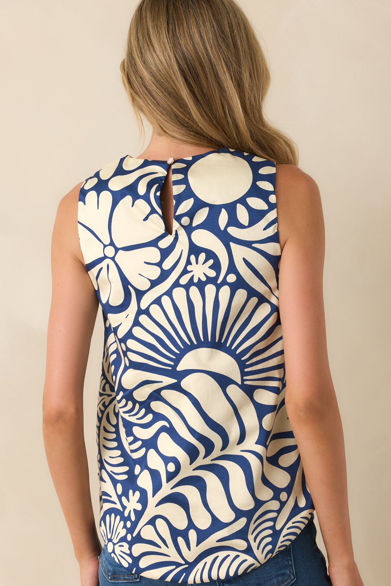 Back view of sleeveless top displaying back keyhole button closure, longer back hem, and solid navy fabric.