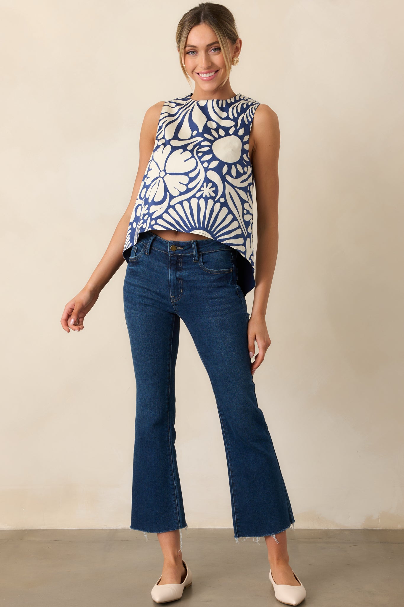 Front view of sleeveless top featuring mixed floral and solid navy design with longer back hem.