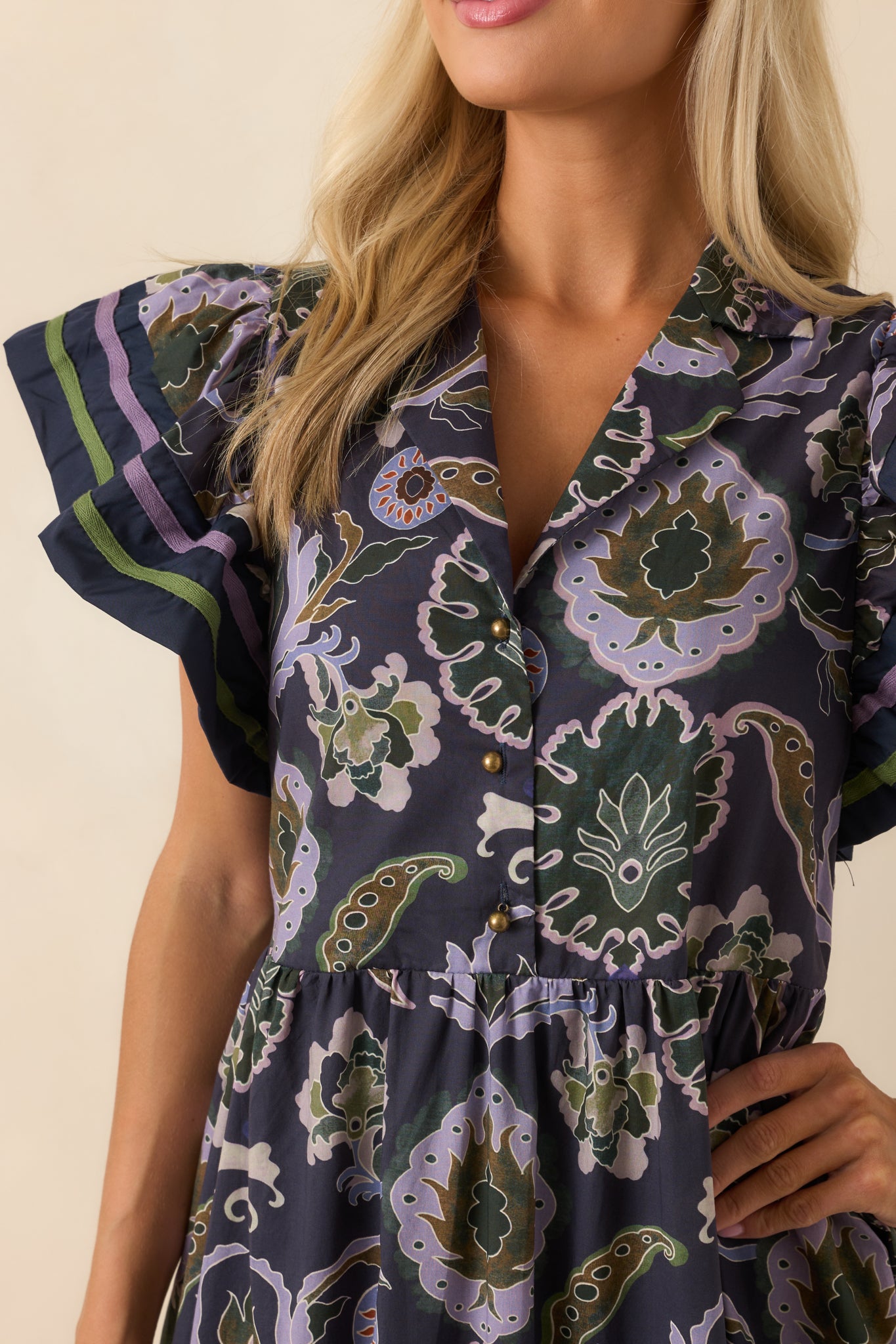 Zoomed-in image showing the notched collar, v-neckline, button front, and green and purple trim details.