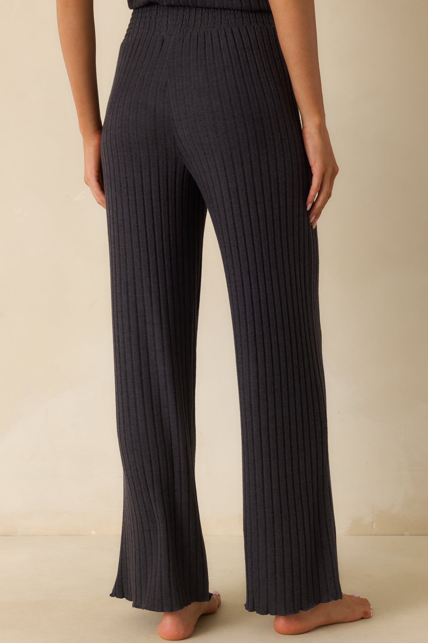 Rear view of the black ribbed pants with a wide leg silhouette and comfortable drape.