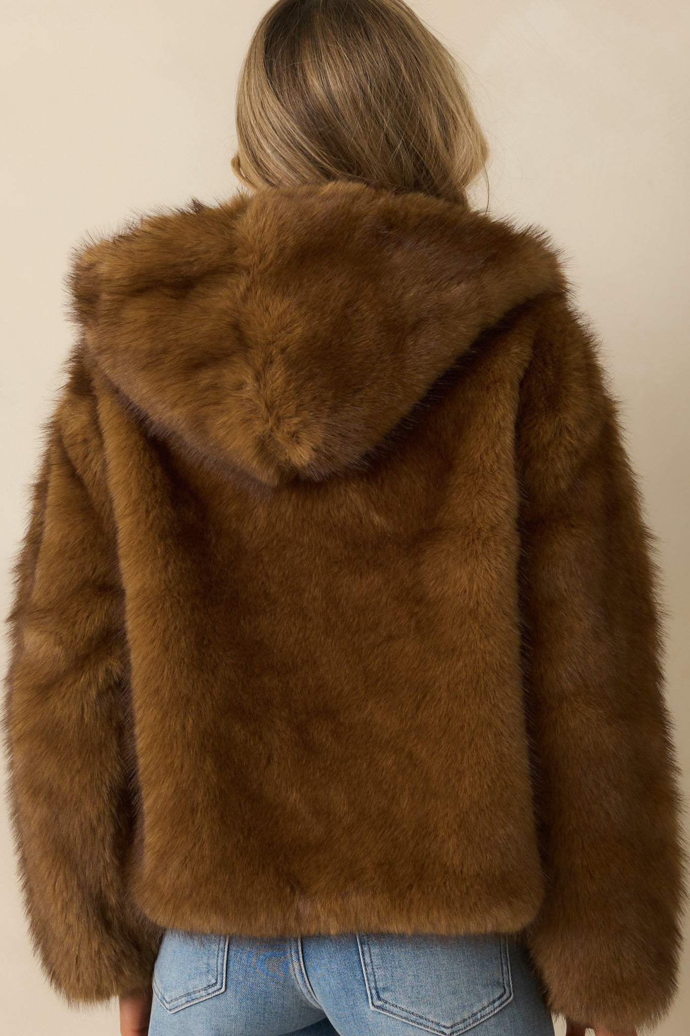 Rear view of the brown faux fur jacket with hood and smooth silhouette.