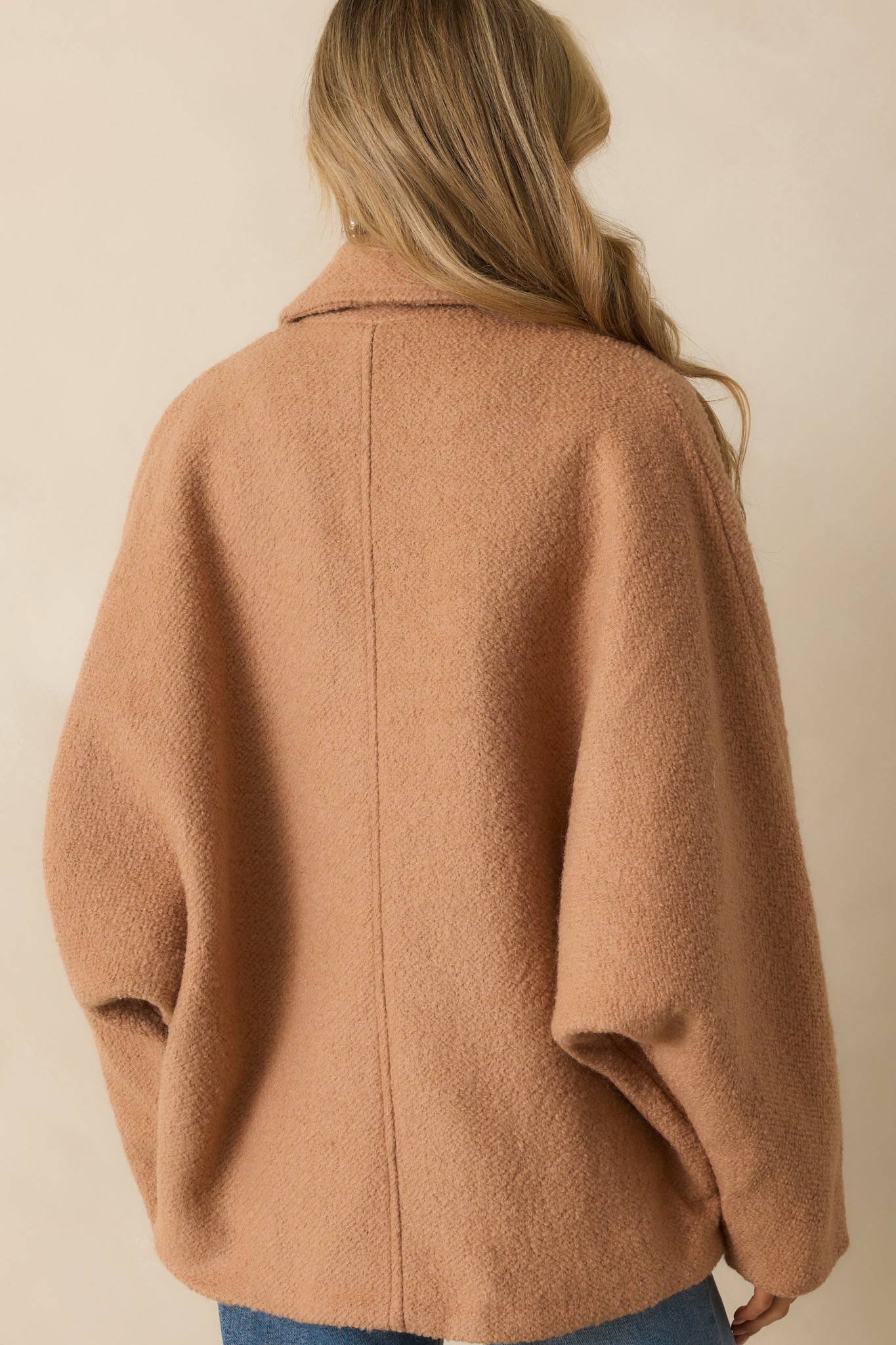 Rear view of the camel brown coat with a straight hemline and clean finish.