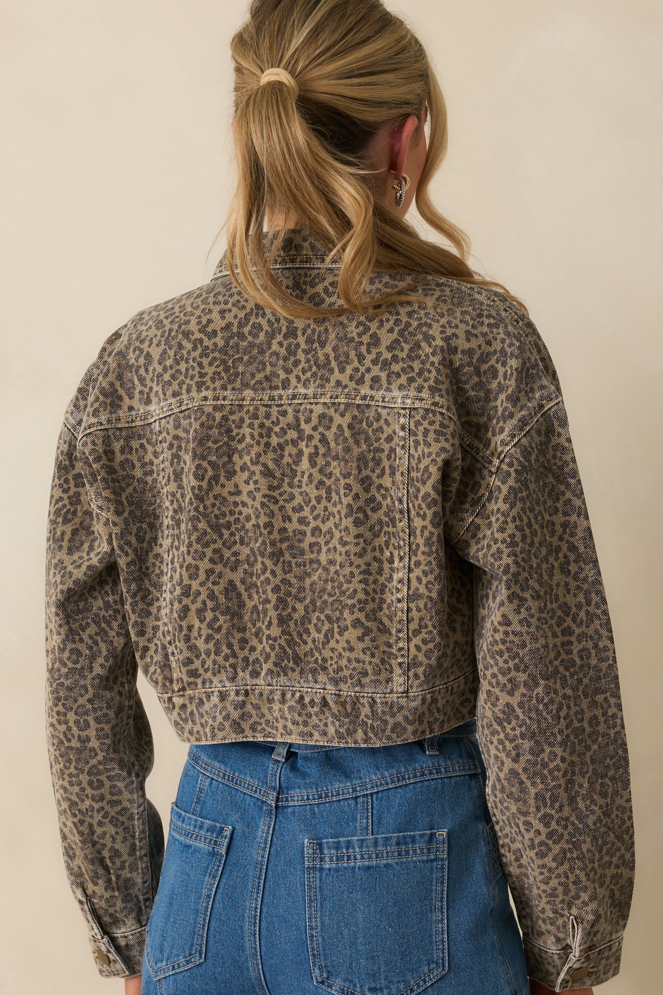 Rear view of the cropped denim jacket with allover leopard print and contrast stitching.