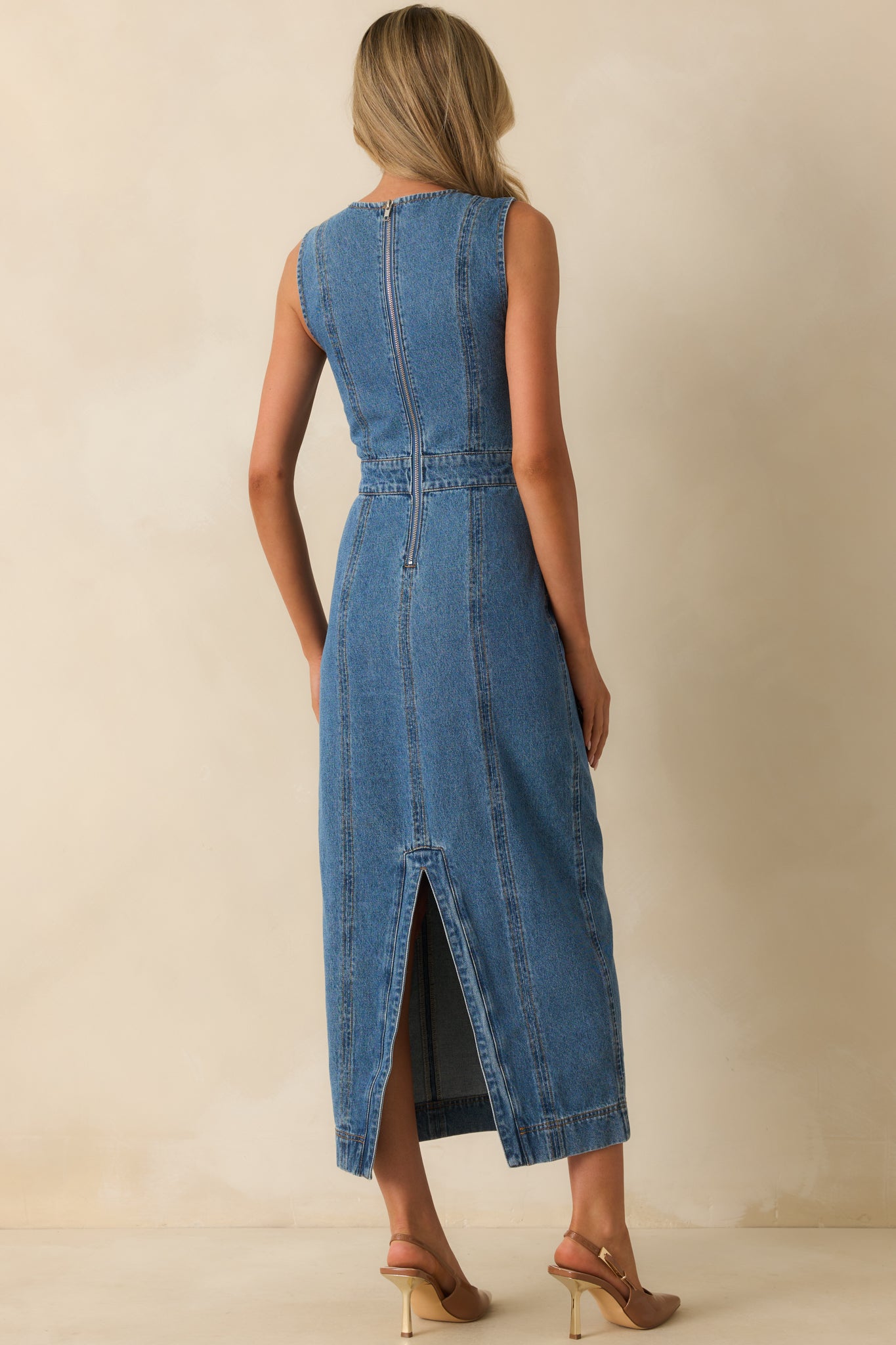 Rear view of the medium wash dress with a back zipper, center seam, and vent slit.