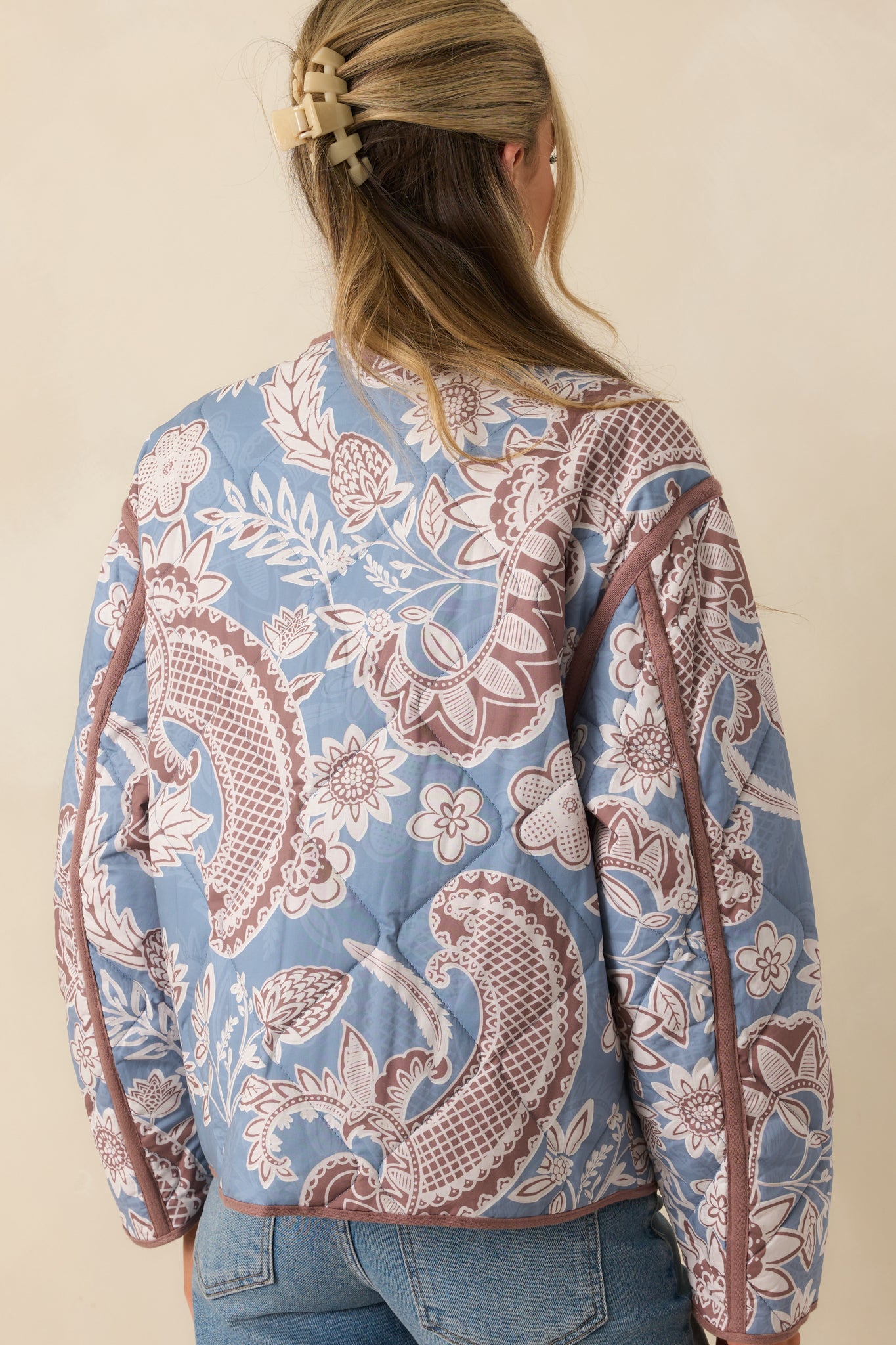 Rear view of the jacket, showing the full quilted floral print across the back with mauve trim accents.