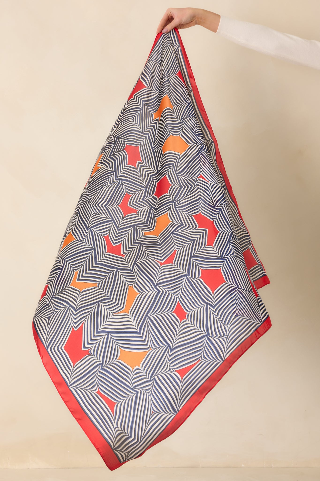 Large red satin scarf arranged to highlight its bold geometric stripes and vibrant color block accents.