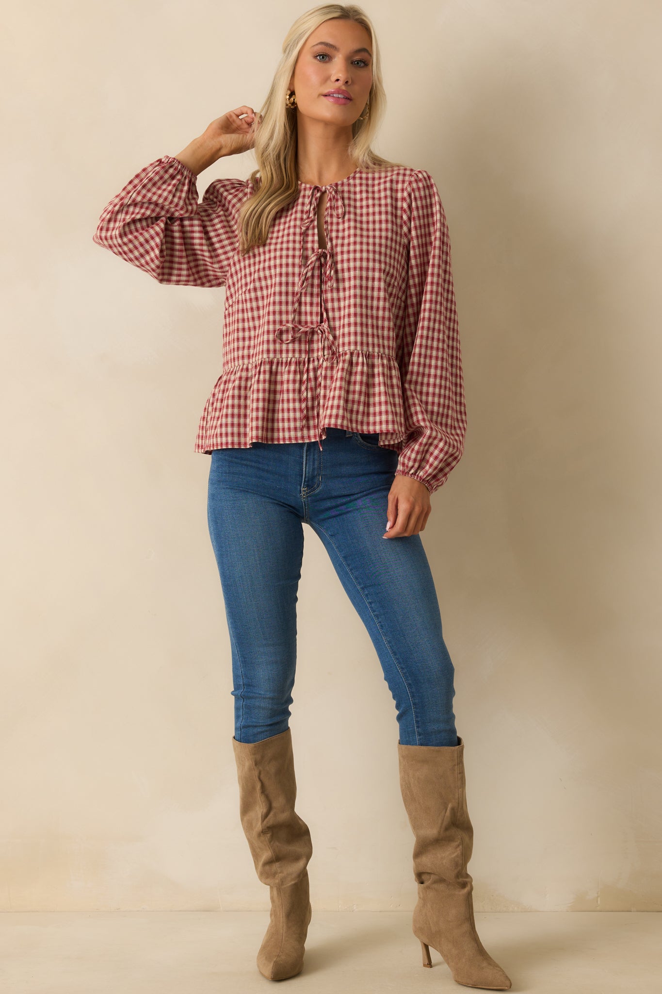 Front view of red and ivory gingham peplum top with tiered bow closure and panel insert.