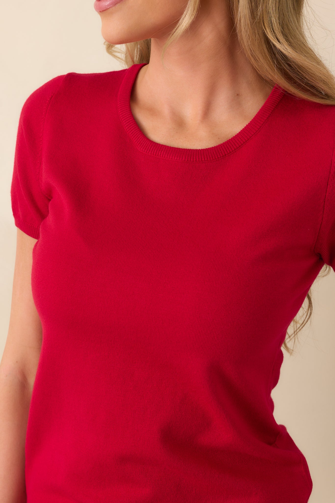 A detailed shot of the red sweater top showing the fine knit texture and ribbed edging.