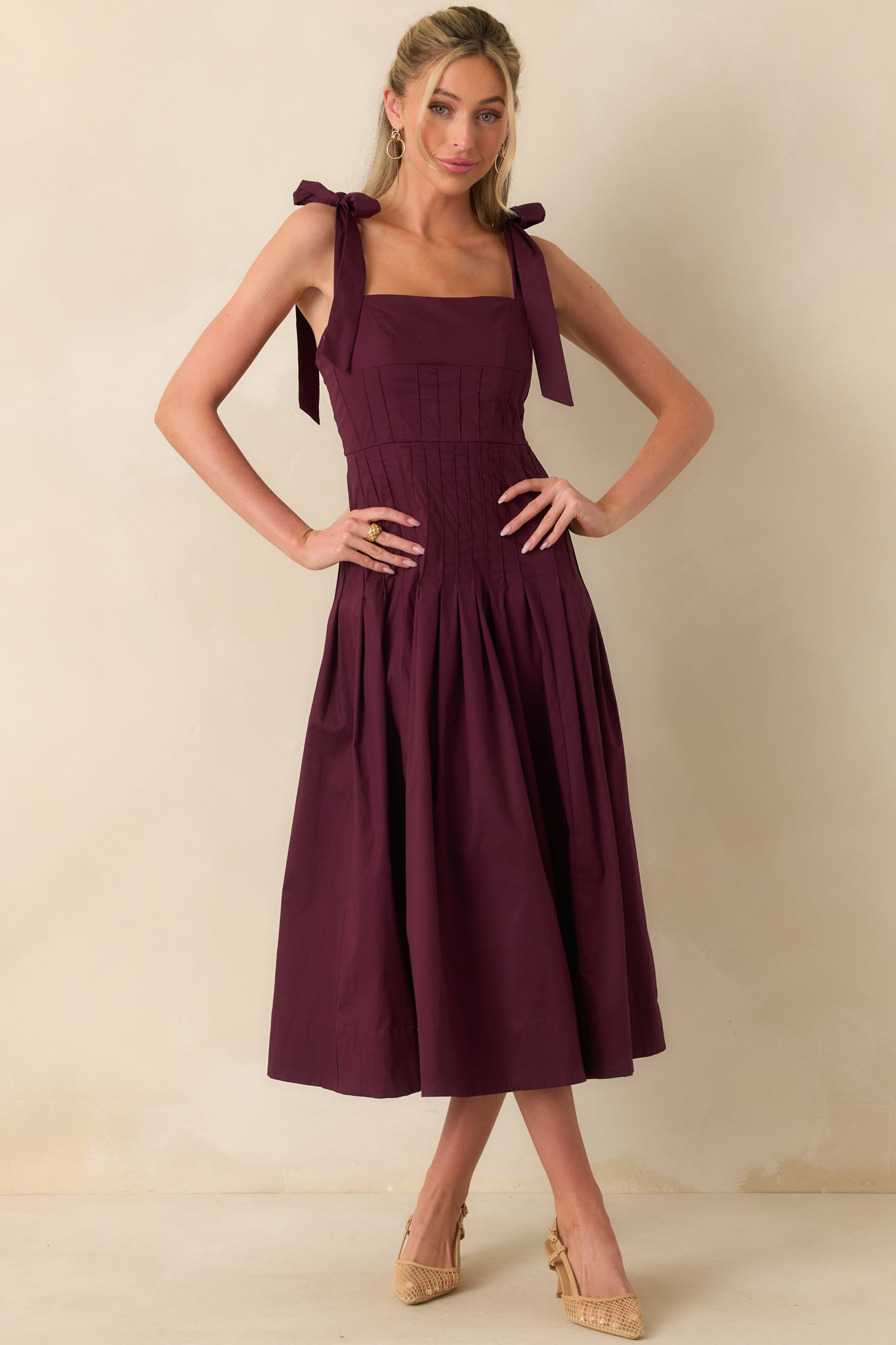 Full-length image of midi dress in sangria purple with fitted bodice, square neckline, and adjustable bow straps.