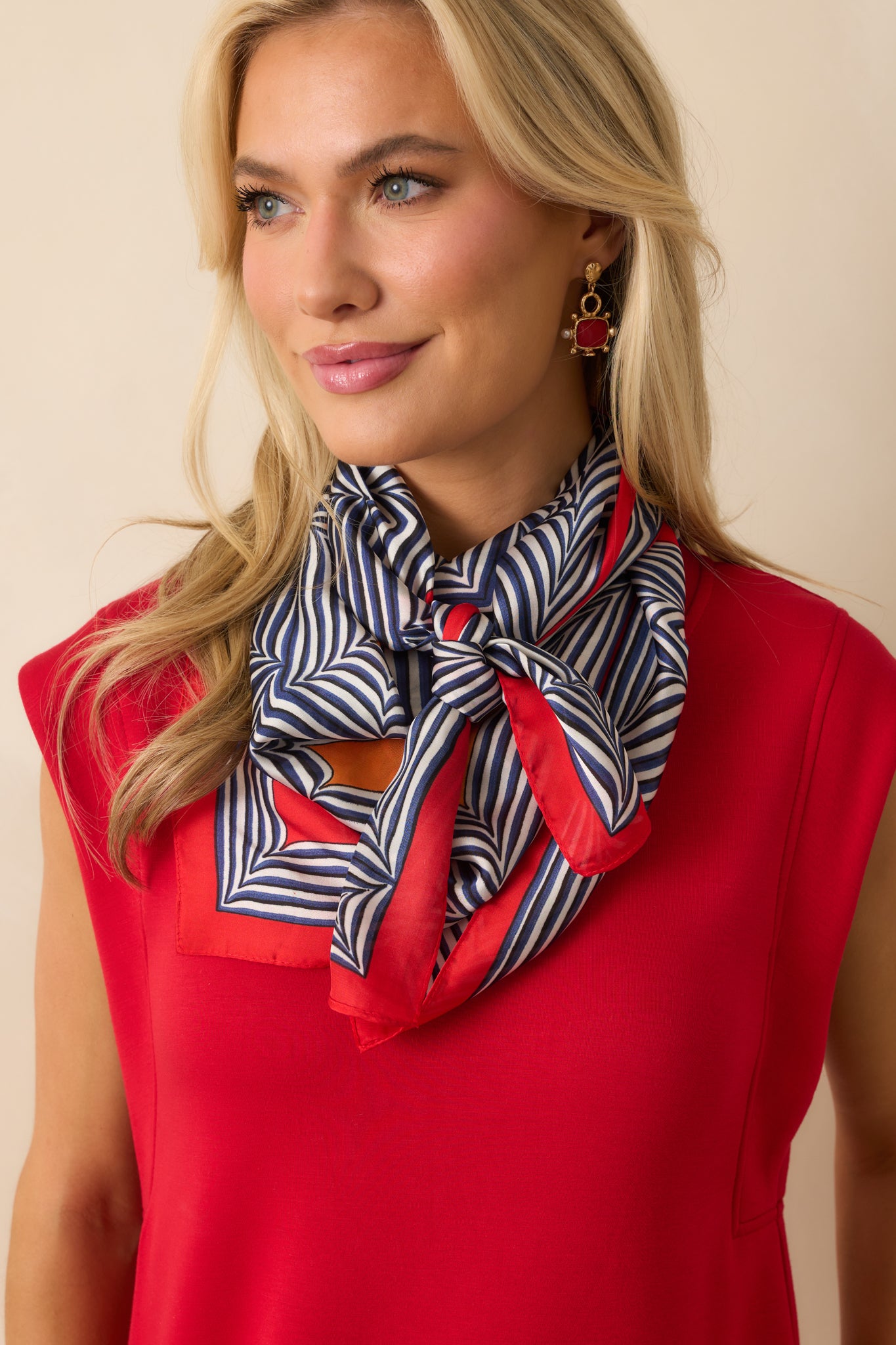 A full view of the scarf being worn, displaying its stripe geometric print with a red border.